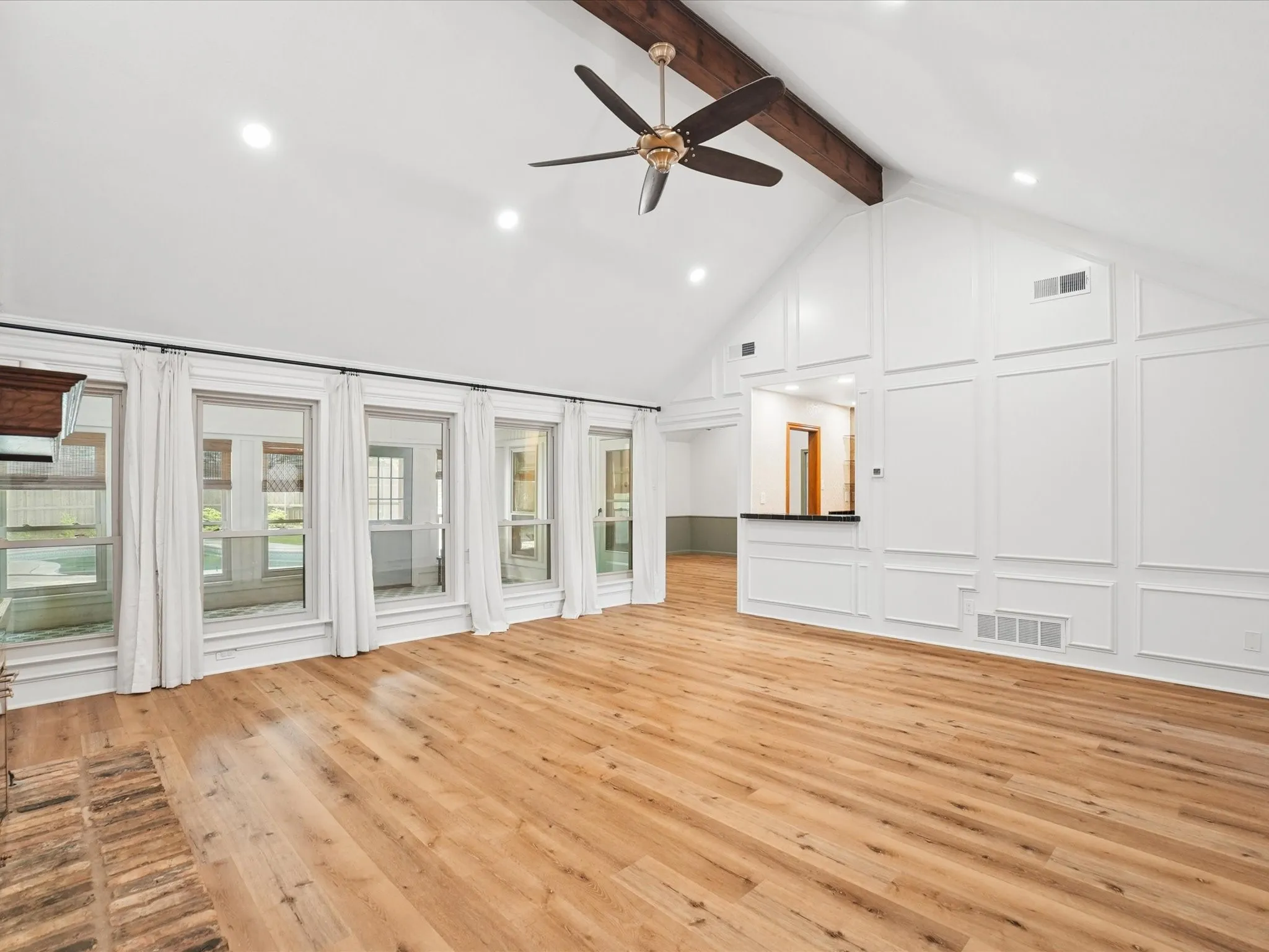 Vaulted ceiling with exposed wood beam, recessed lighting, and a ceiling fan