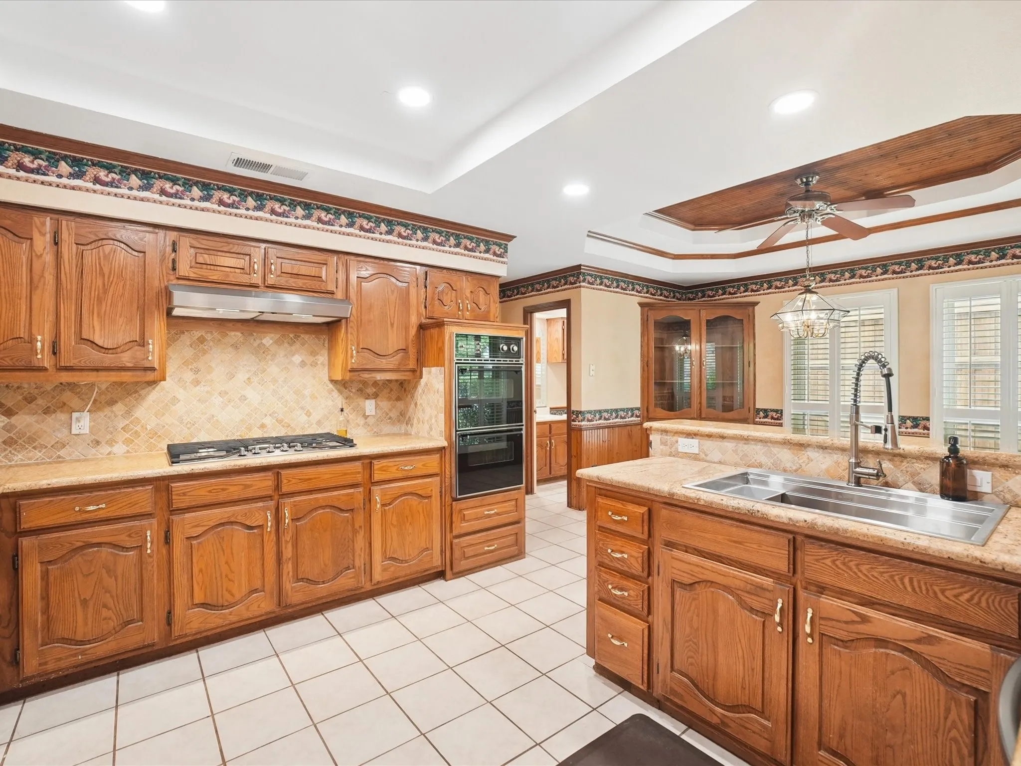 Kitchen featuring wood-finish cabinetry, tile flooring, recessed lighting, and a double basin sink