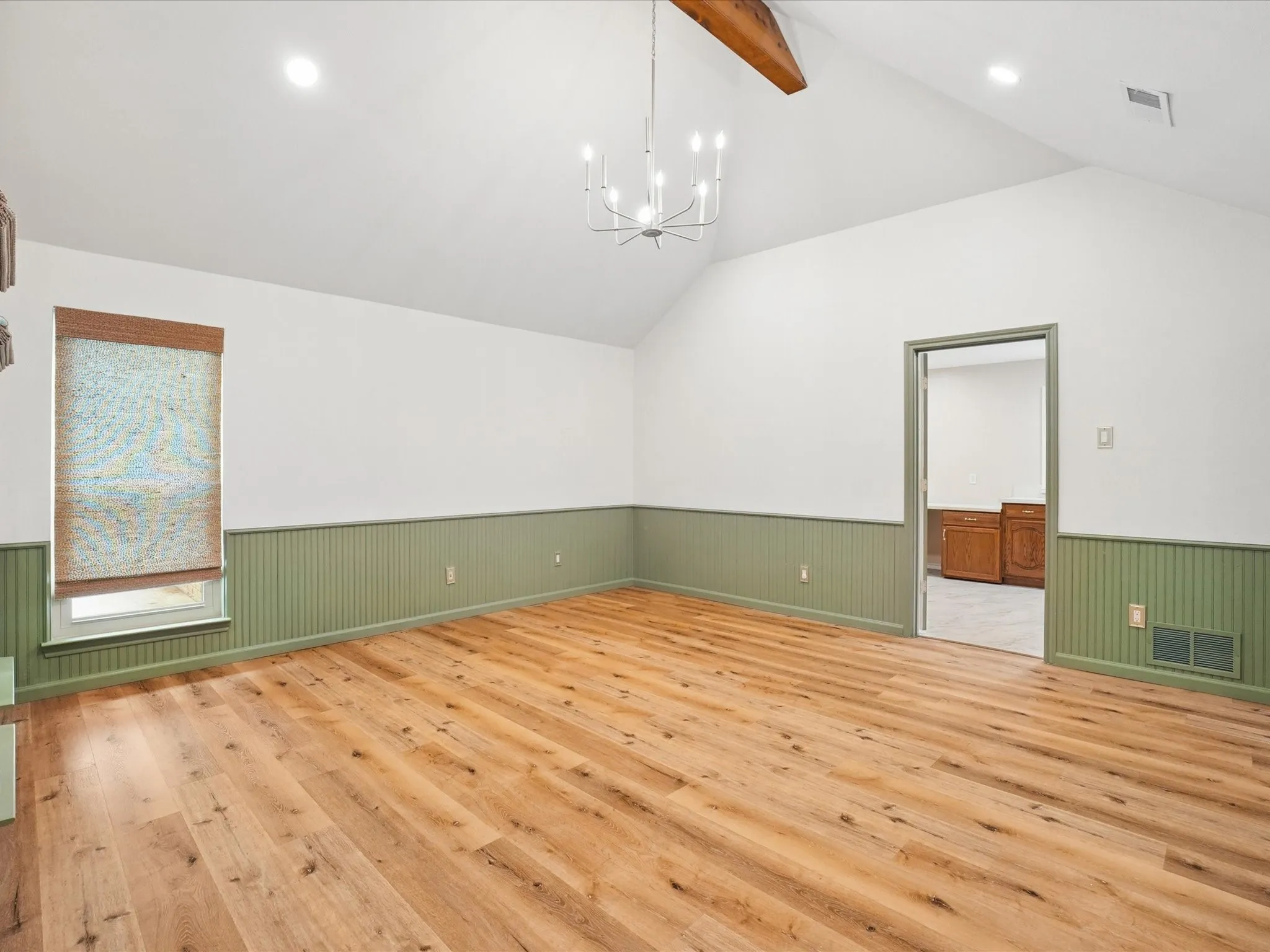 Vaulted ceiling with exposed wood beam, wood-finish flooring, recessed lighting, and chandelier