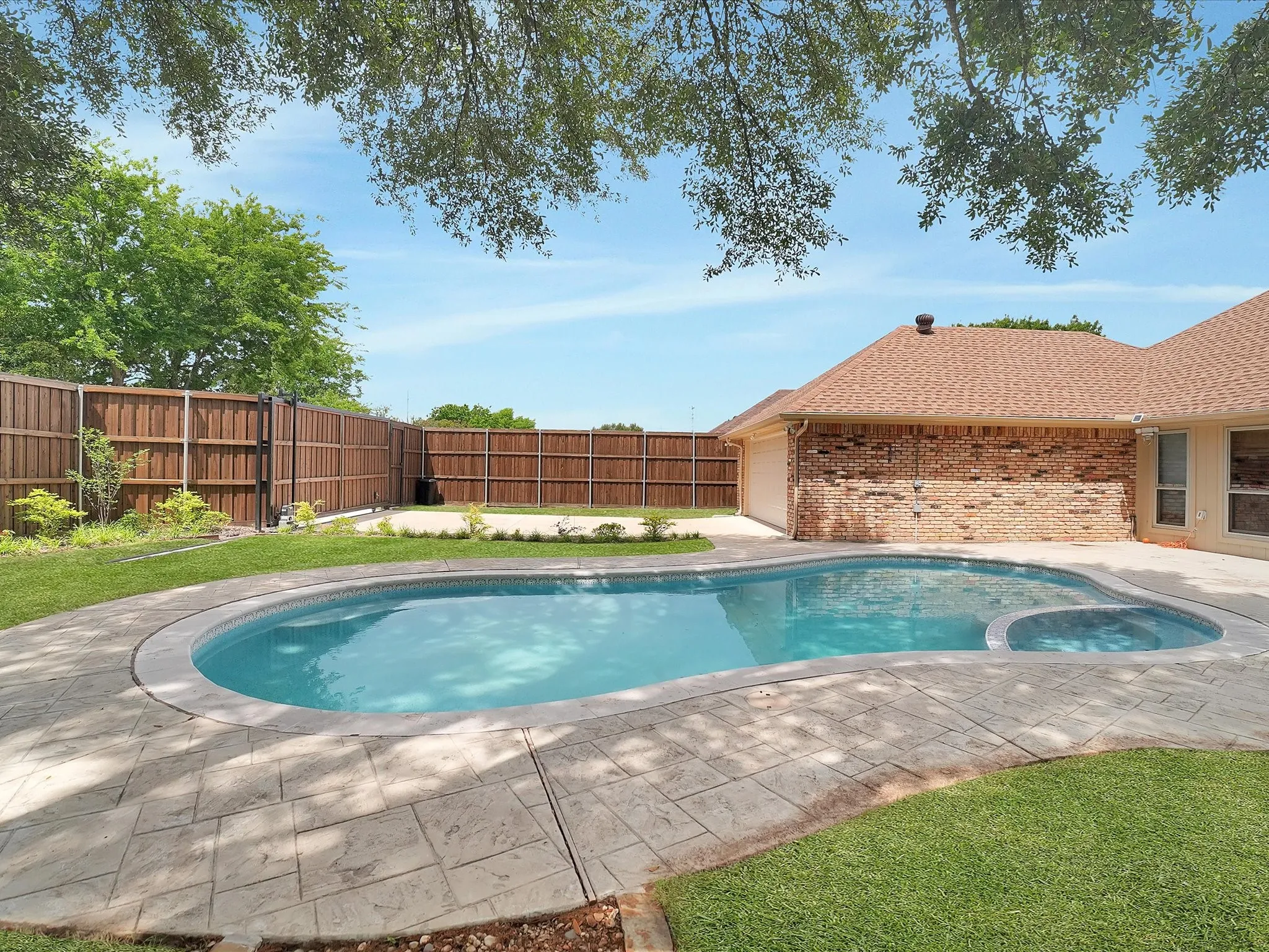 Outdoor swimming pool with integrated spa and stamped concrete surround