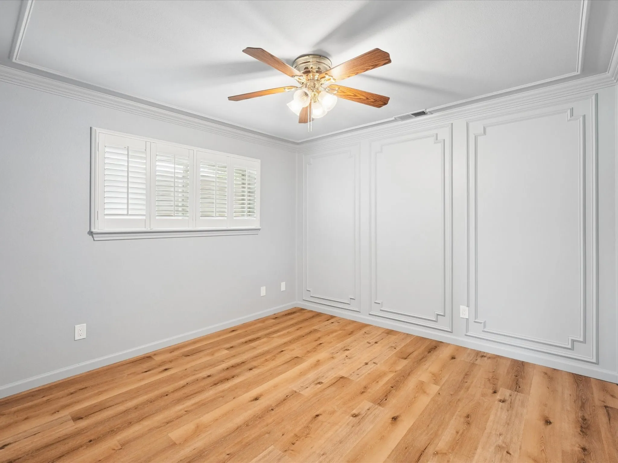 Wood-finish flooring throughout, crown molding, and decorative wall paneling