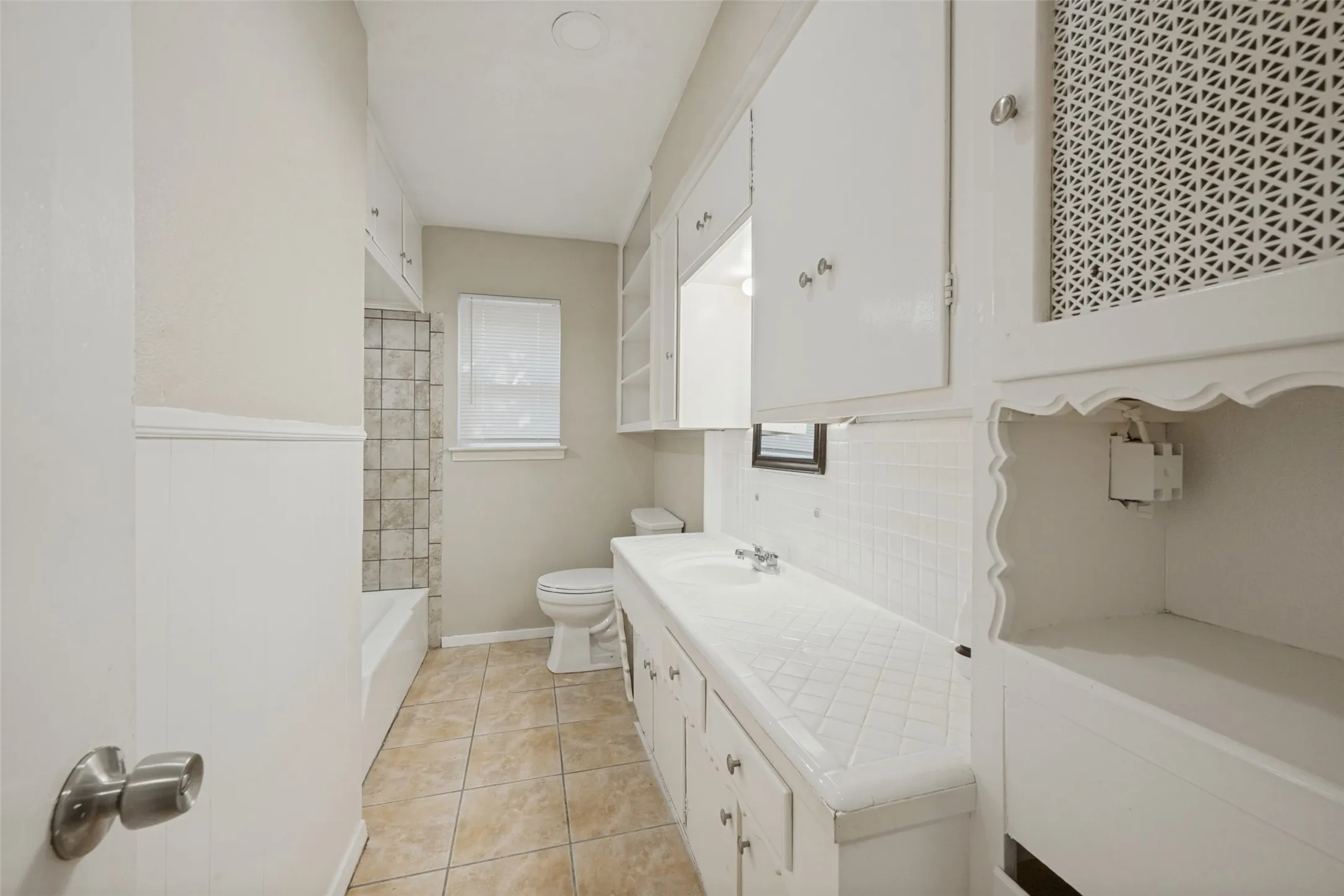 Built-in shelving and cabinetry, tiled flooring, integrated sink, and white subway tile backsplash