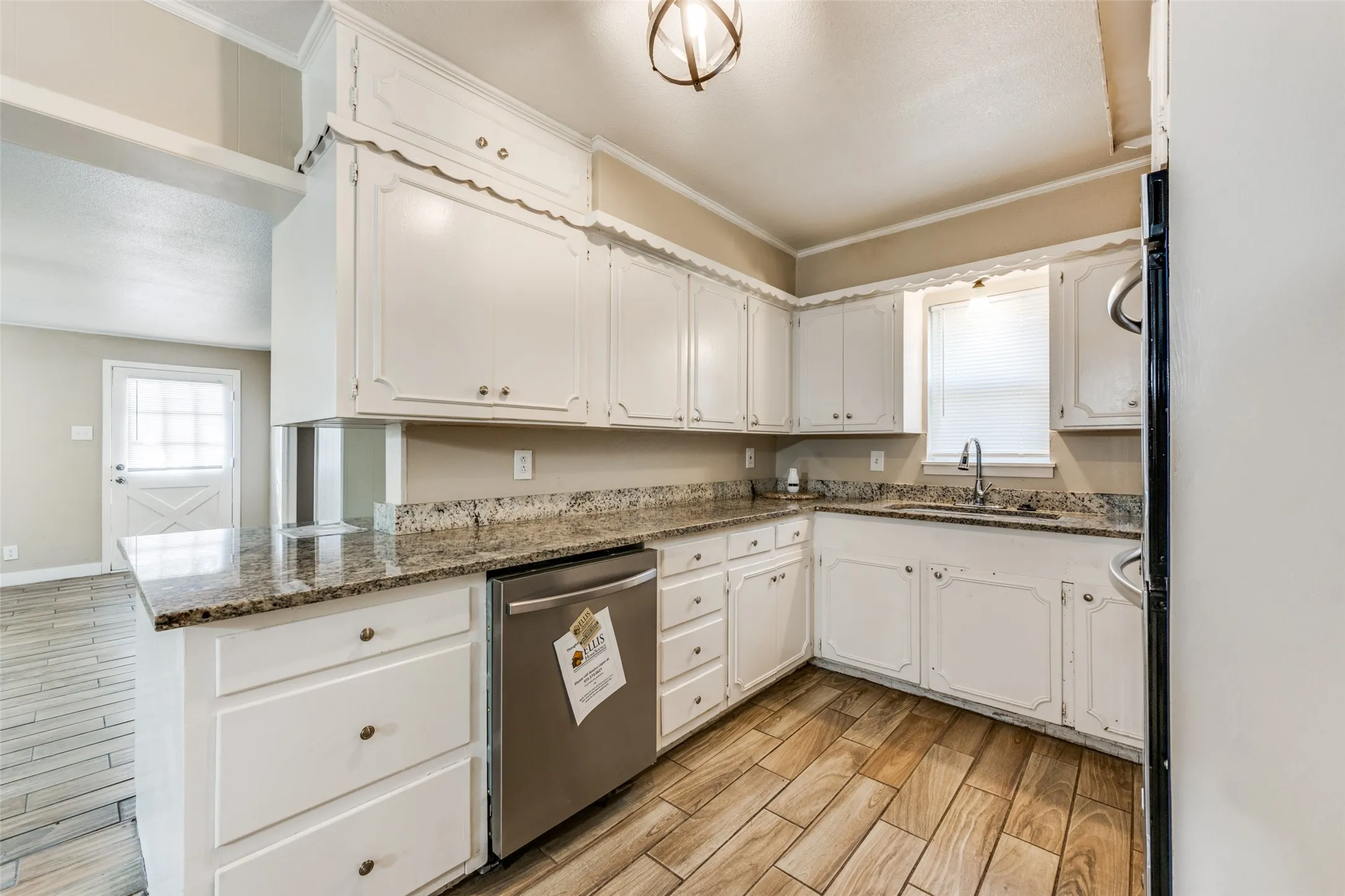 Kitchen featuring white cabinetry, granite countertops, a stainless steel dishwasher, and wood-finish flooring
