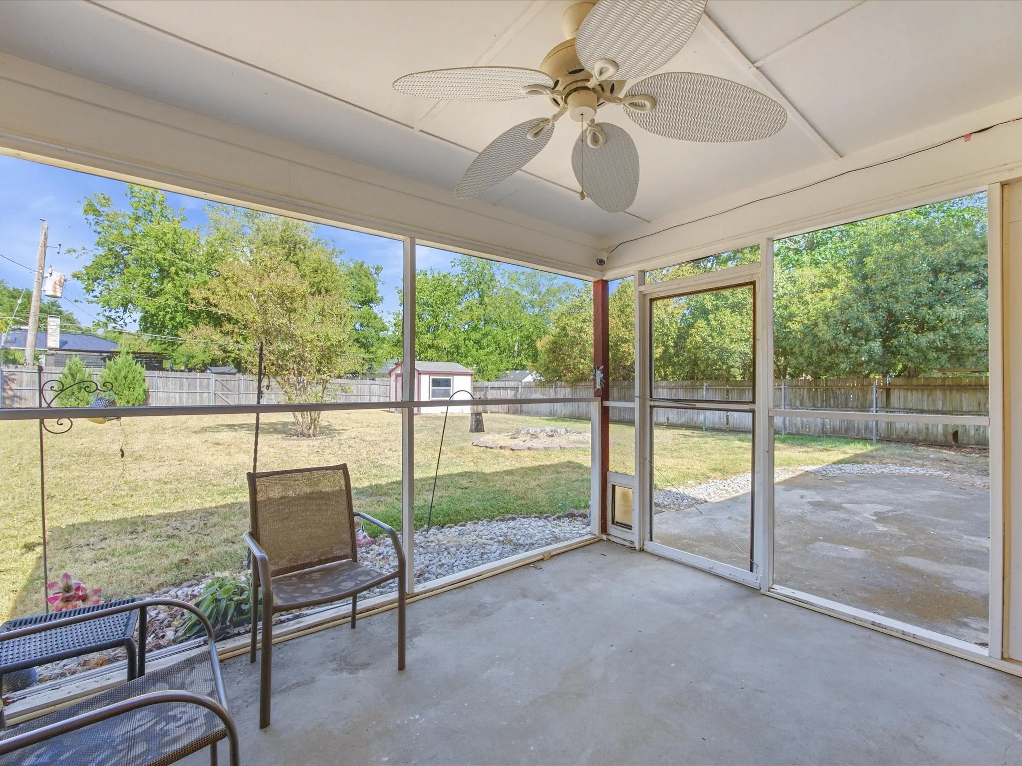 Screened-in porch with a ceiling fan, concrete flooring, and an exterior screen door