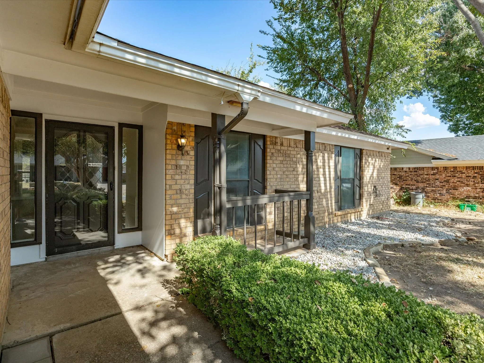 Brick exterior with a covered porch entry, decorative glass front door, and adjacent sidelight windows