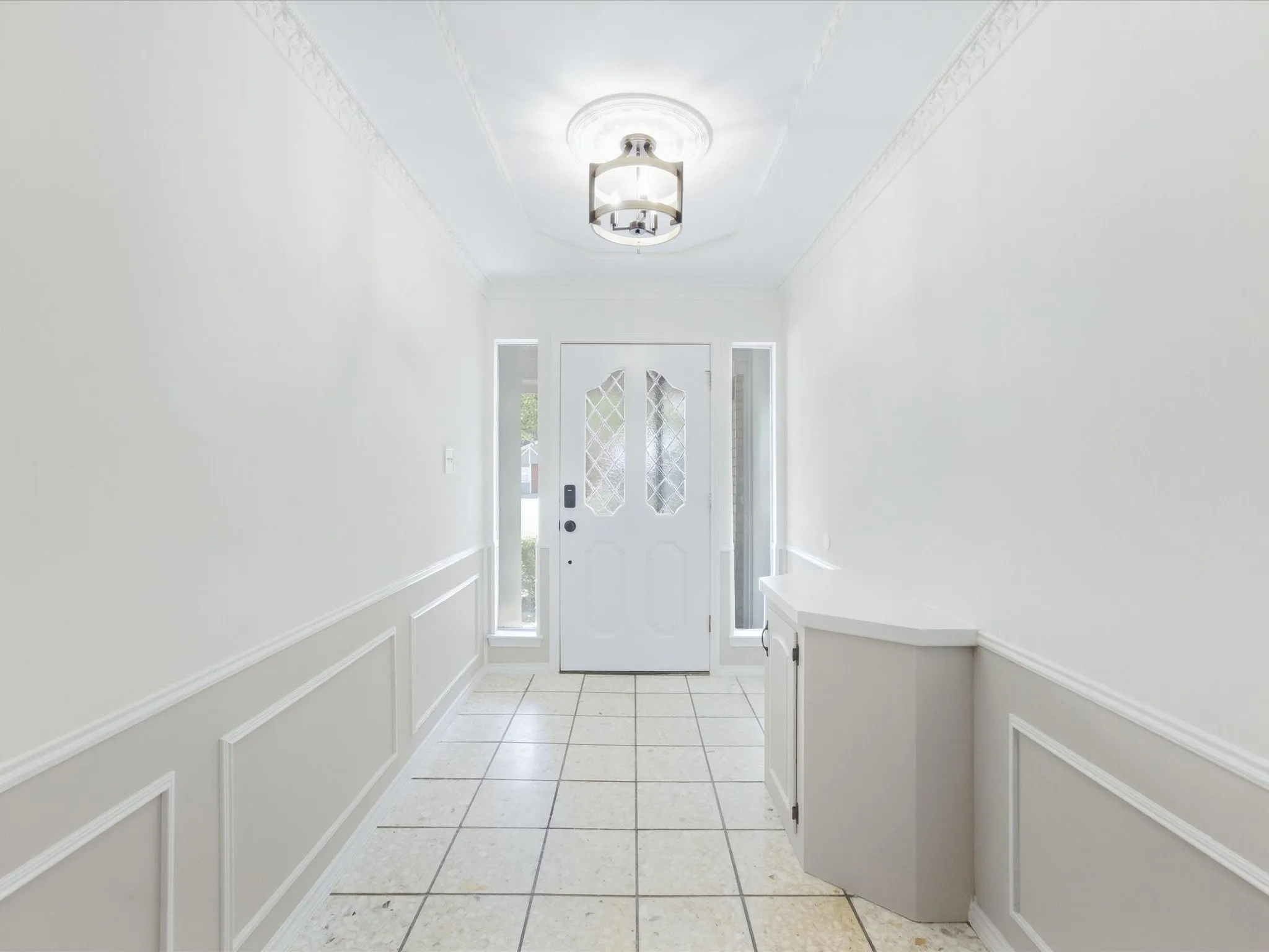 Foyer featuring wainscoting, decorative crown molding, tile flooring, and a decorative flush-mount light fixture