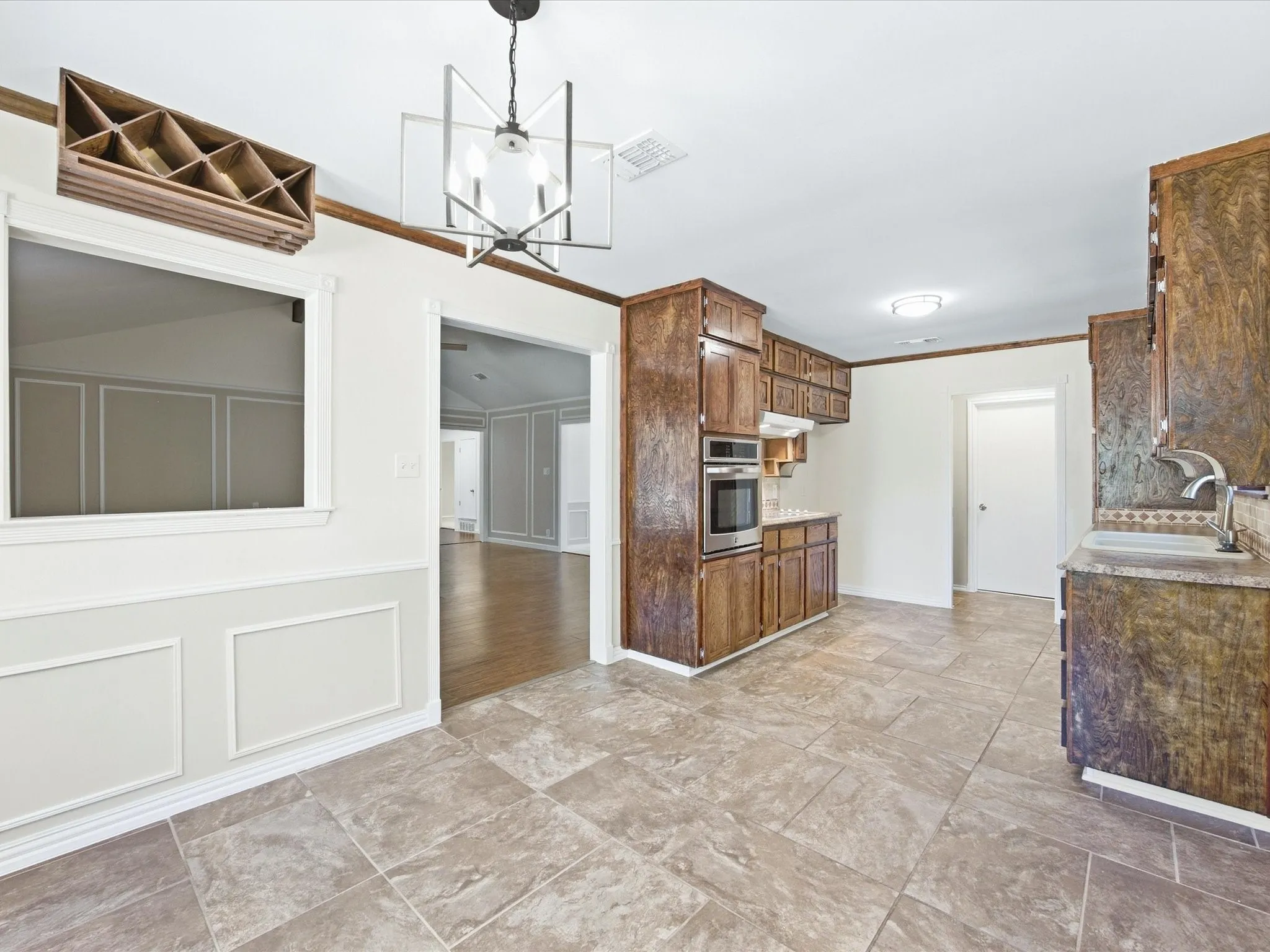 Kitchen featuring tile flooring, wood cabinetry, built-in oven, and a double basin sink