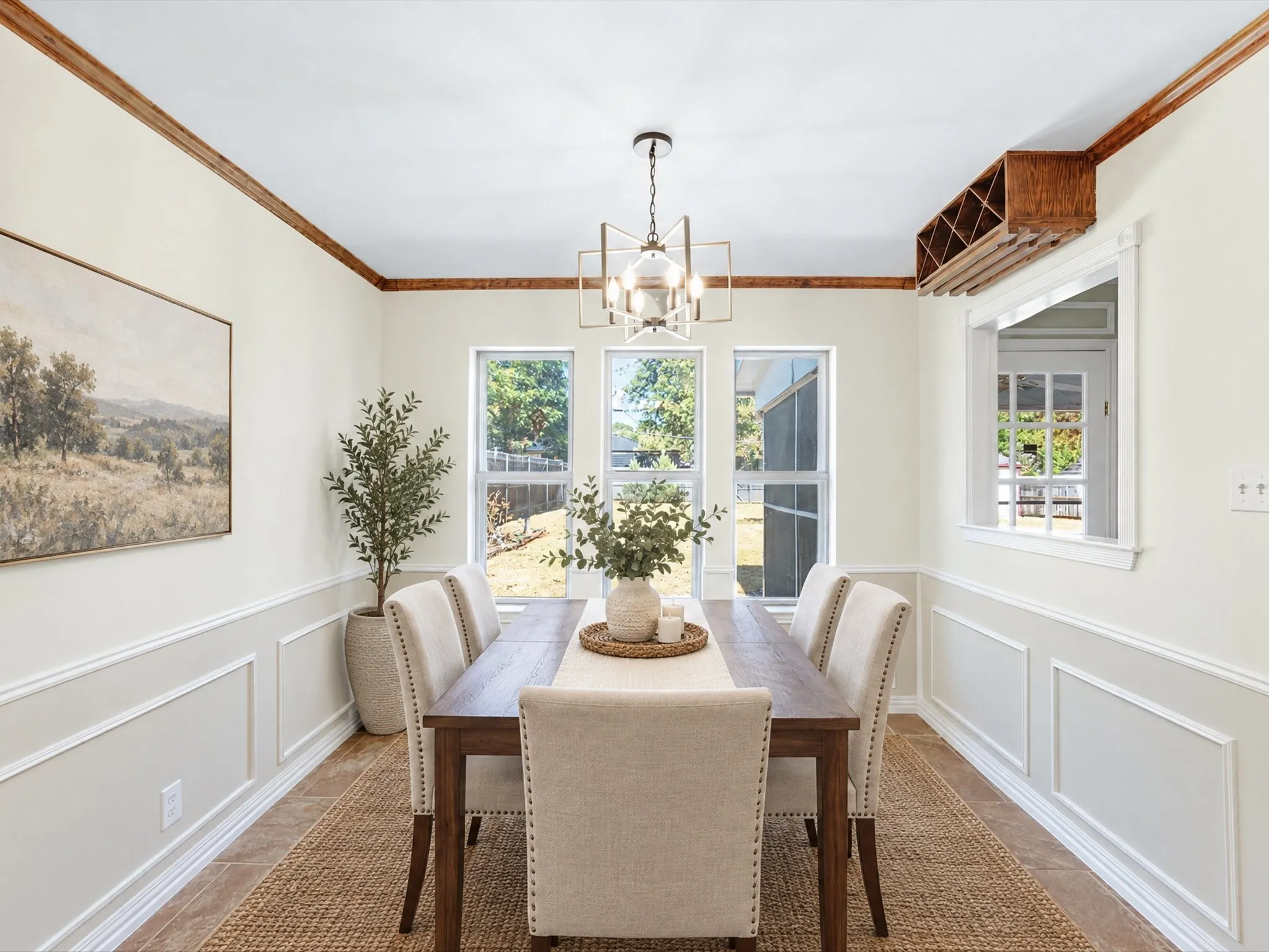 VIRTUALLY STAGED!Hardwood crown molding, wainscoting details, tile flooring, built-in wine rack, and a geometric chandelier