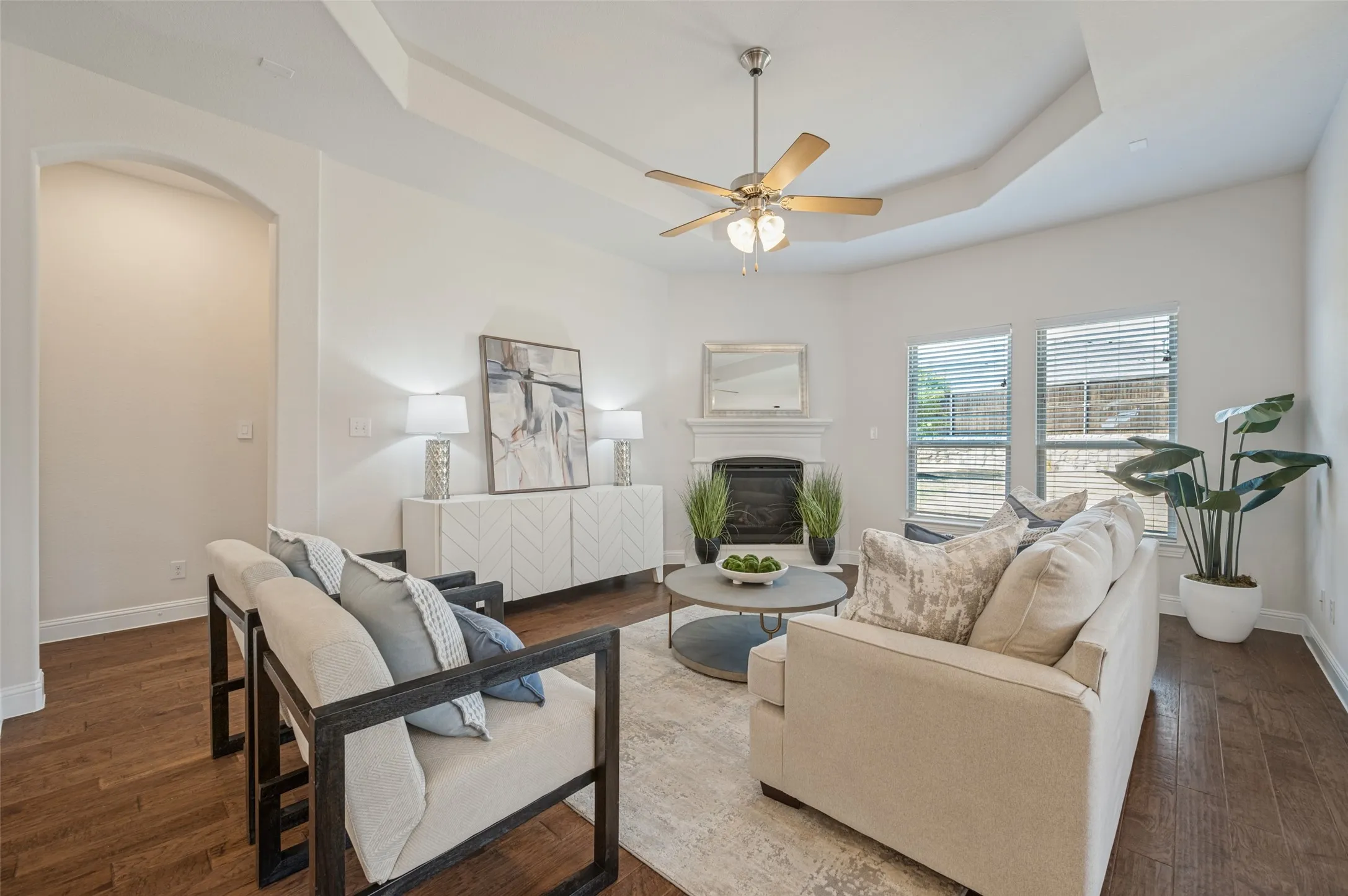 Tray ceiling, recessed lighting, wood-finish flooring, ceiling fan, and a fireplace with mantle