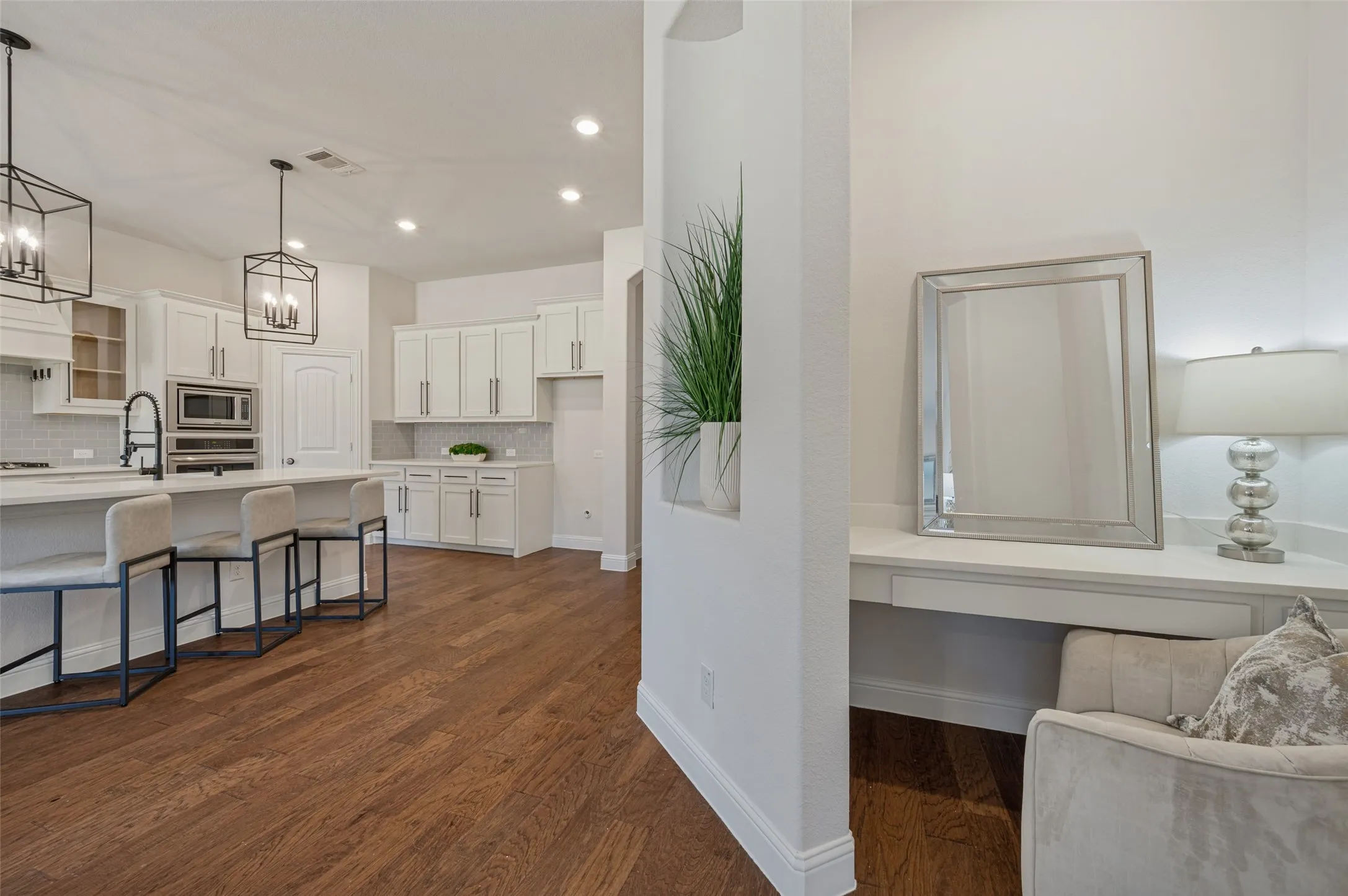 Expansive wood-finish flooring, white shaker-style cabinetry, and recessed lighting