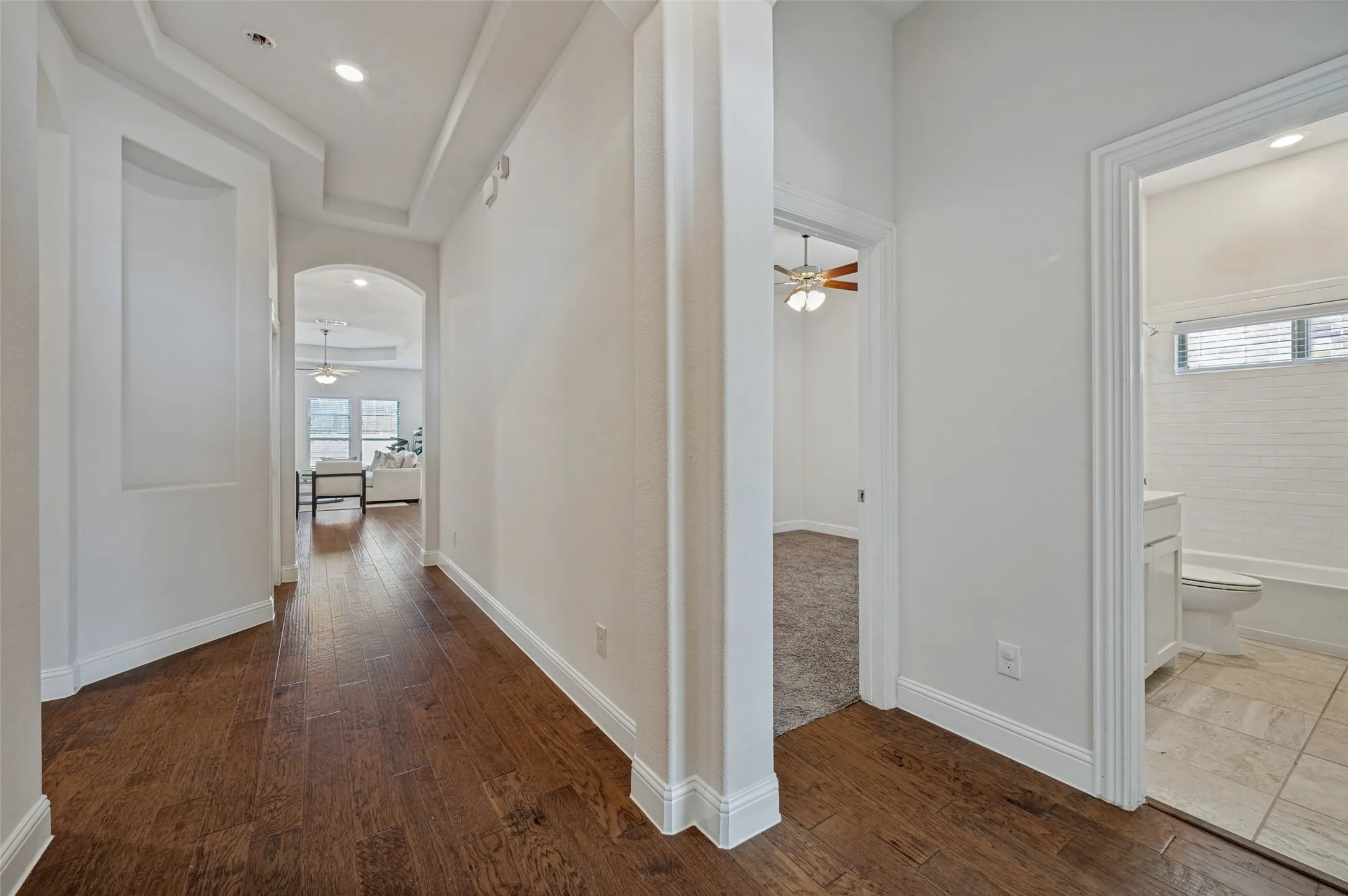 Hallway featuring wood-finish flooring, recessed lighting, arched doorways, and a built-in wall niche