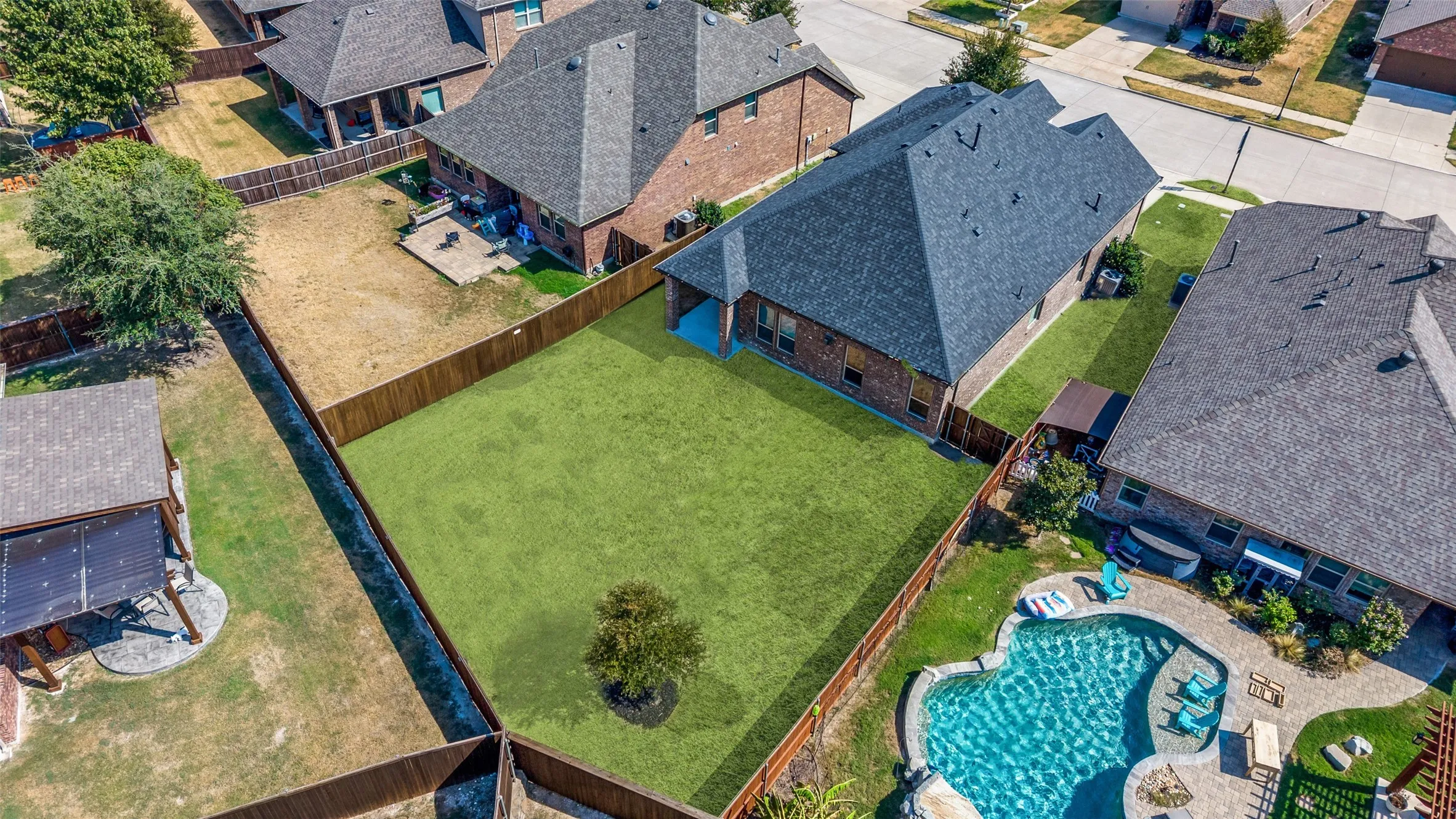 Expansive fenced backyard featuring a manicured lawn and a single ornamental tree