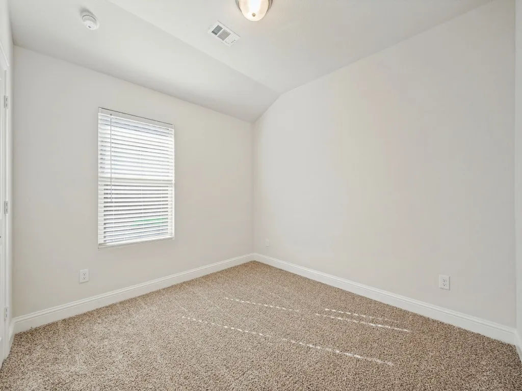Neutral-toned carpeting with white trim, window with blinds, and a ceiling-mounted light fixture