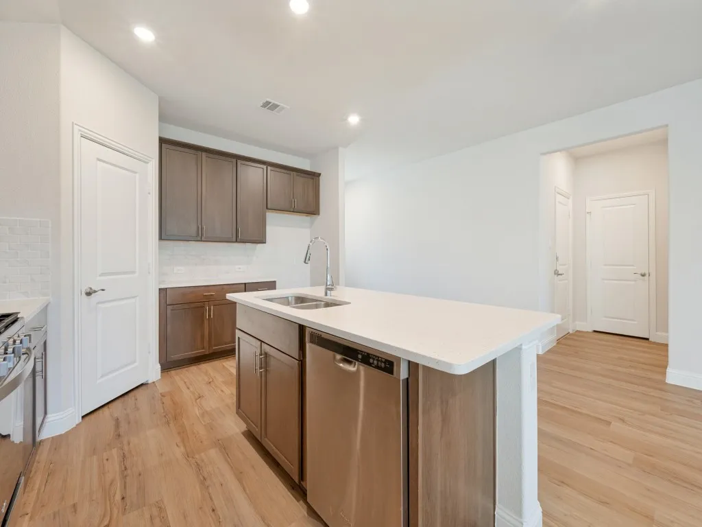 Kitchen featuring wood-finish flooring, recessed lighting, and an island with an integrated stainless steel dishwasher