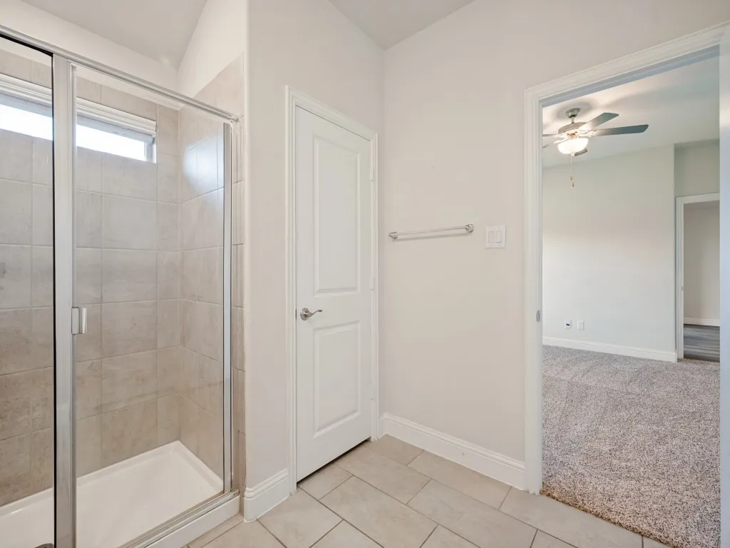 Glass-enclosed shower with ceramic tile surround and a transom window