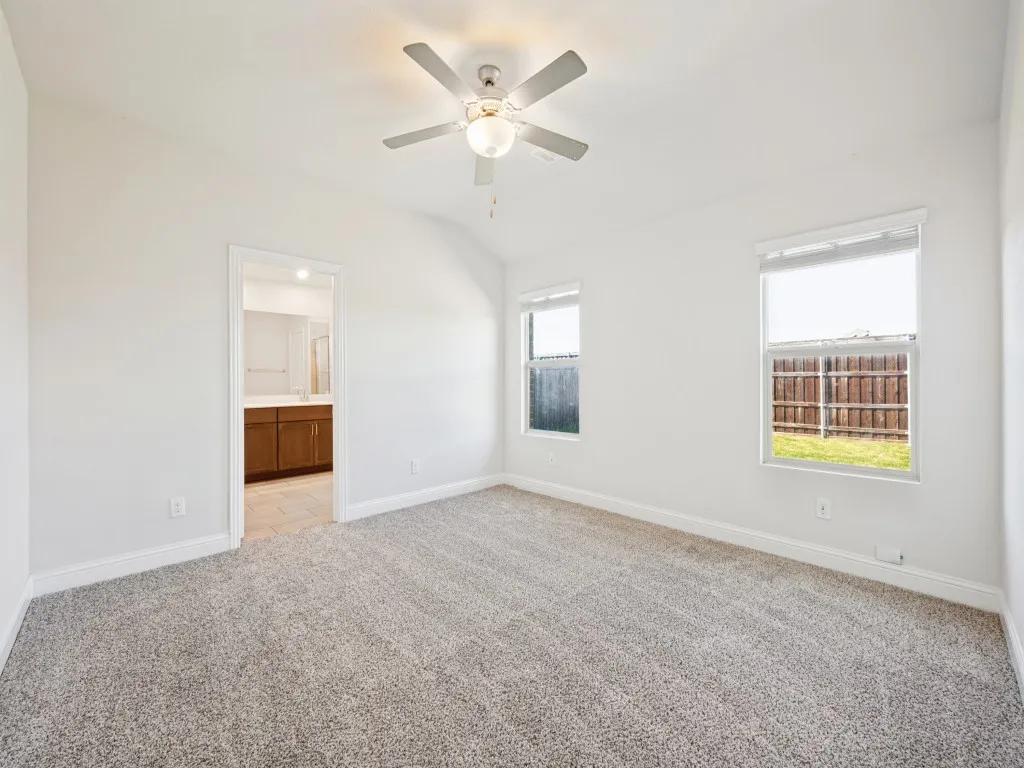 Vaulted ceiling with a ceiling fan, carpeted flooring, and multiple windows