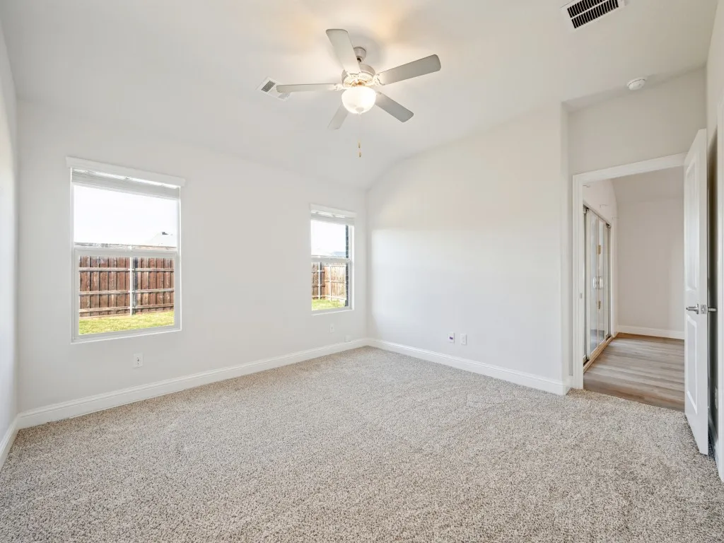 Carpeted room with two windows, a ceiling fan, and a neutral color palette