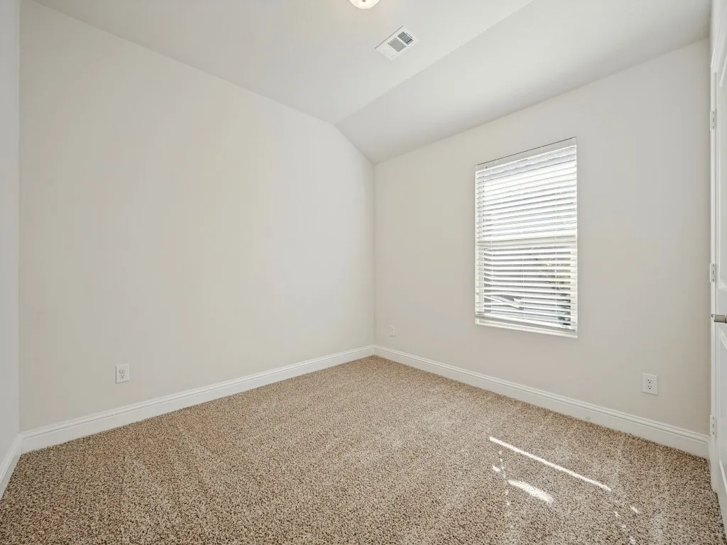 Neutral-toned carpeting, white walls, window with horizontal blinds, and a white interior door