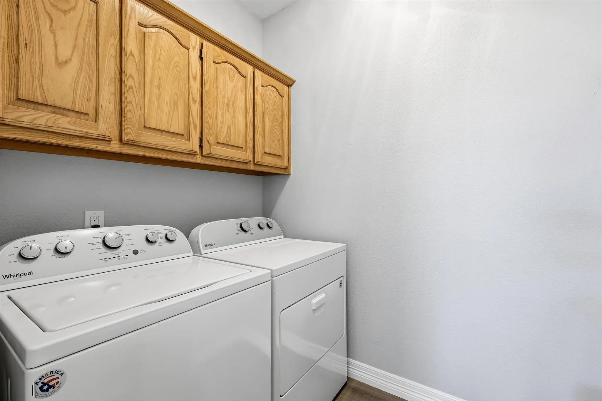 Laundry space is ready for use, featuring WASHER AND DRYER and built-in overhead wooden cabinets