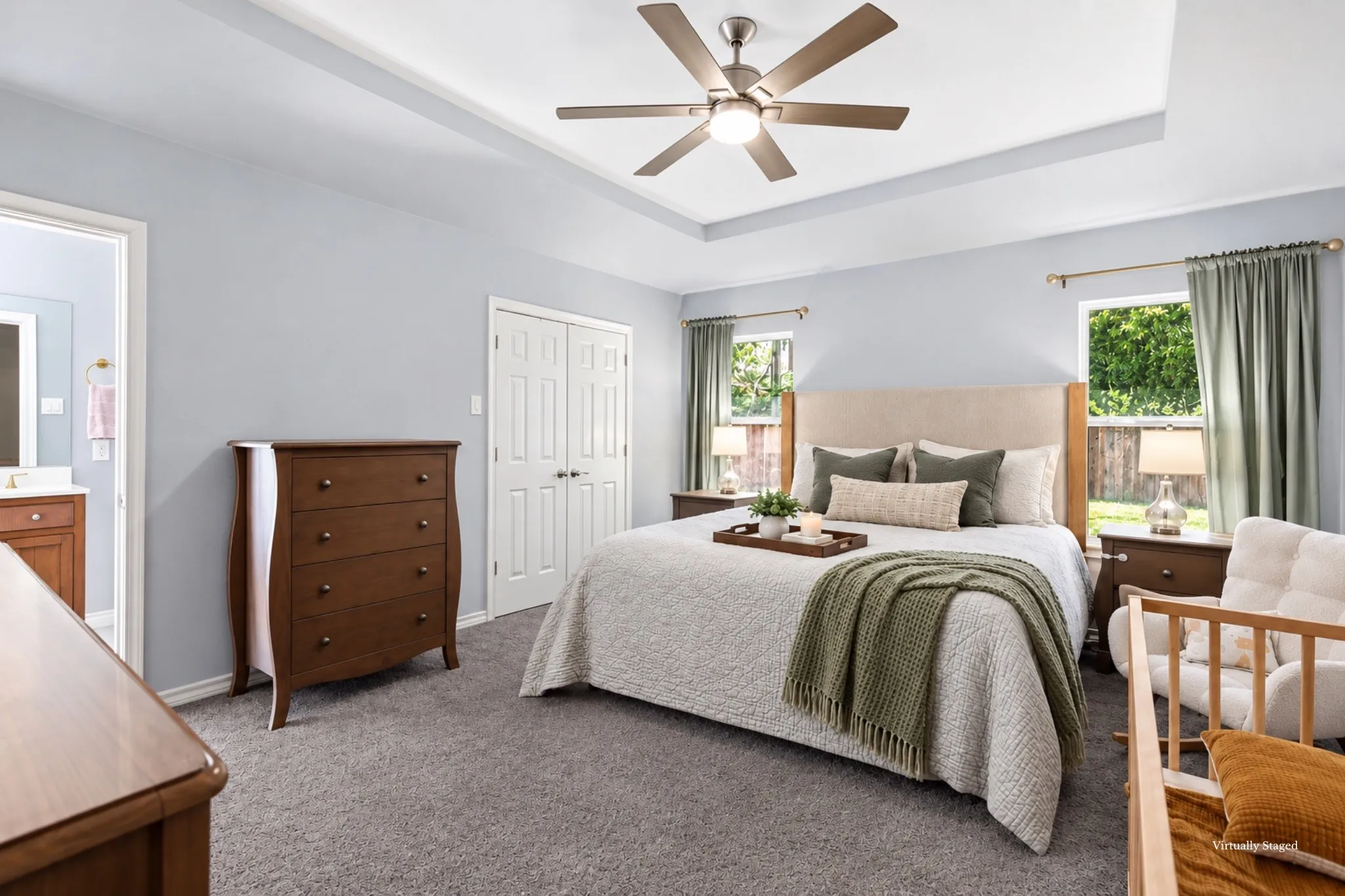 Primary ensuite features natural lighting, windows, tray ceiling, a ceiling fan, carpeted floors, and large double-door walk-in closet!