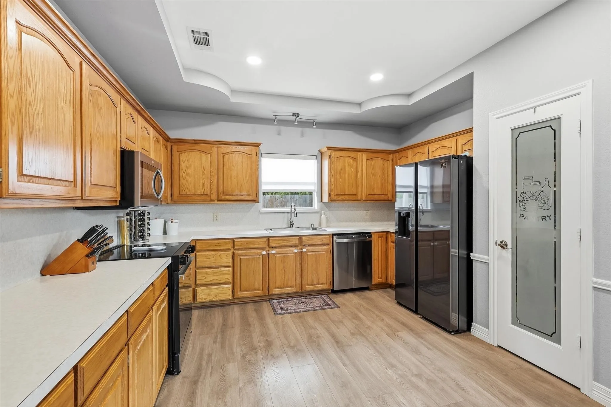 Light and bright kitchen with electric cooktop, dishwasher, microwave, and single basin stainless steel sink