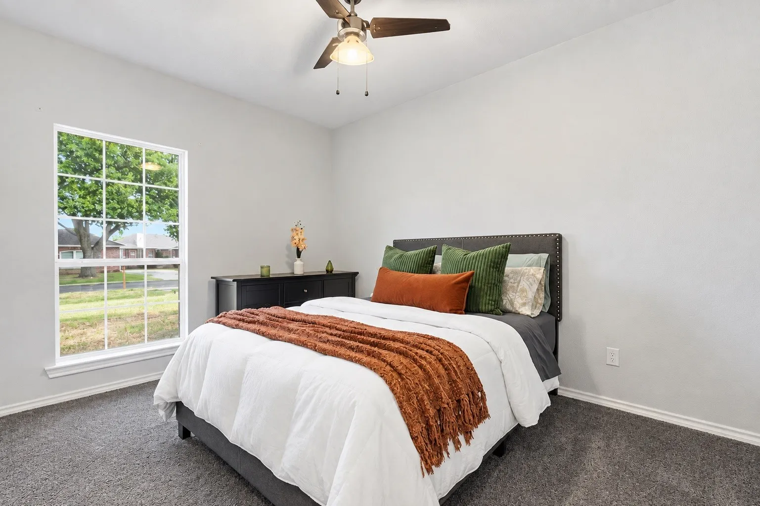 Bright and airy secondary downstairs bedroom with ceiling fan, spacious walk-in closet, carpeted flooring and window overlooking the front yard street area