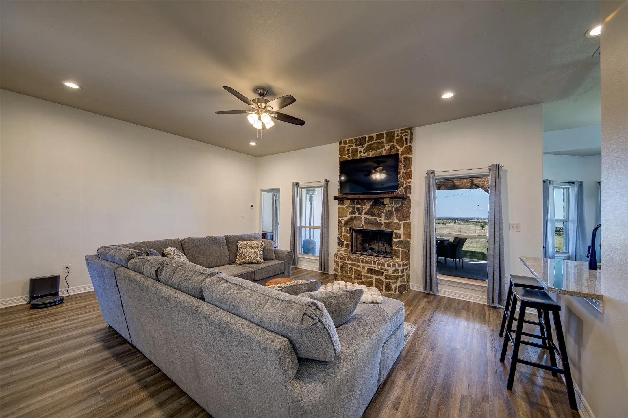 Living room with view of back yard and stone wood burning fireplace.