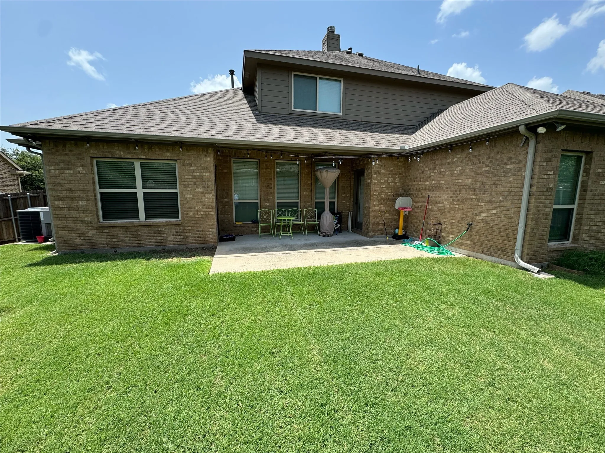 Rear view of house with a patio, a lawn, and central air condition unit