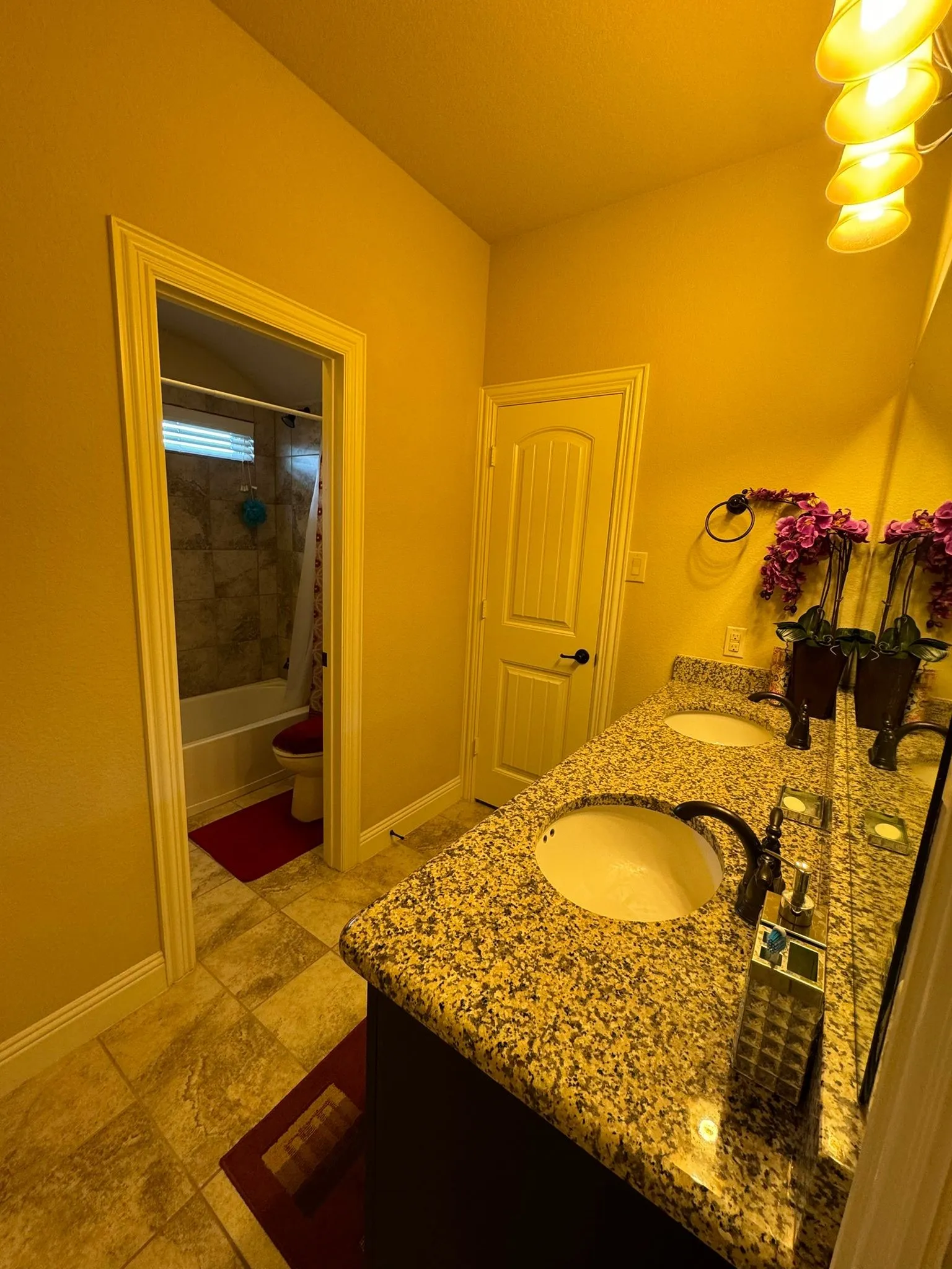 Full bathroom featuring toilet, tile patterned floors, double sink vanity, and tiled shower / bath combo