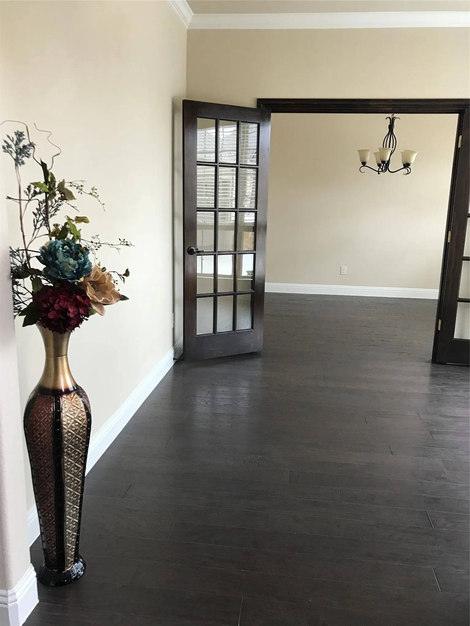 Spare room with dark hardwood / wood-style flooring, an inviting chandelier, crown molding, and french doors