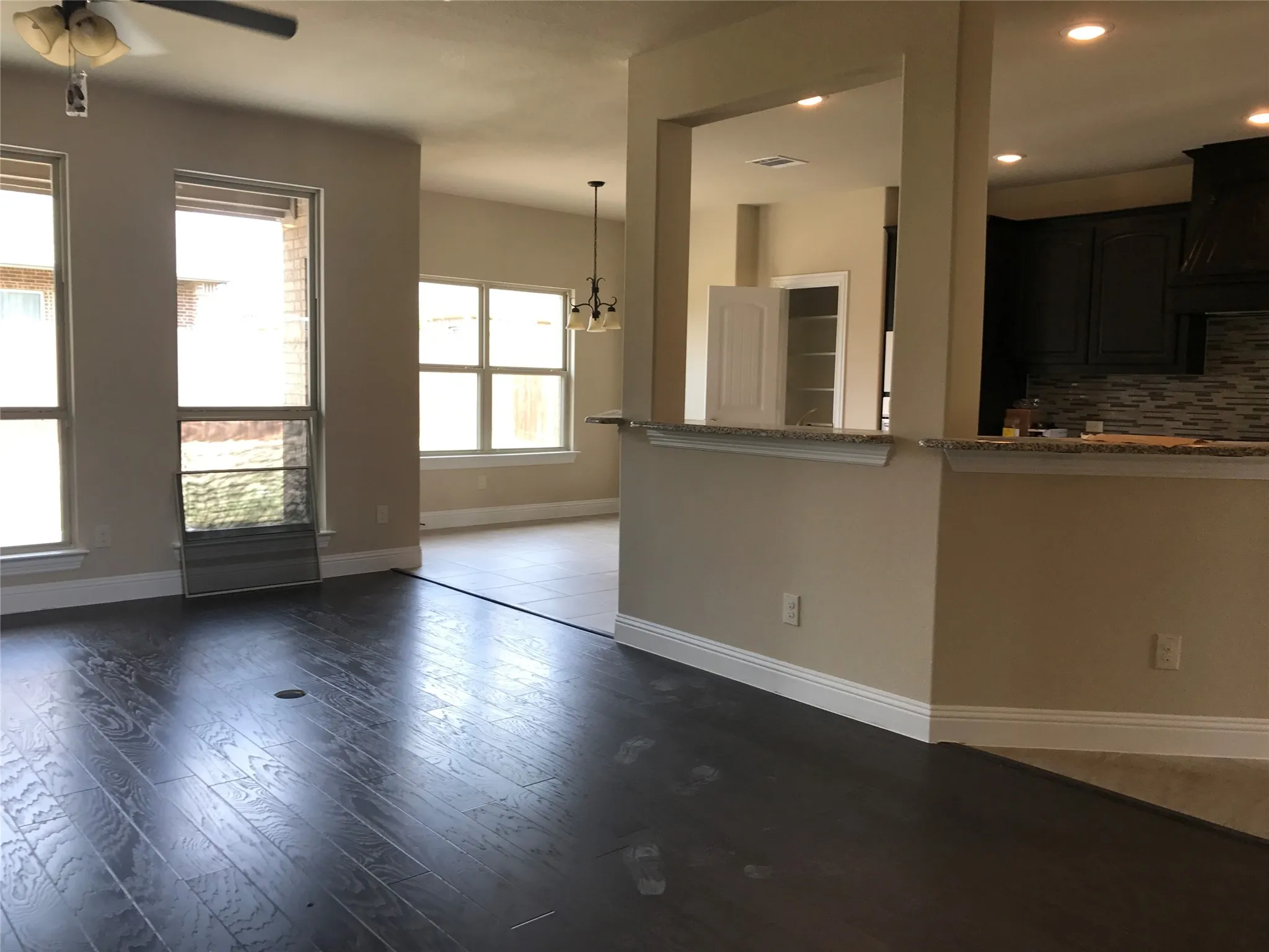 Unfurnished living room featuring ceiling fan with notable chandelier and wood-type flooring