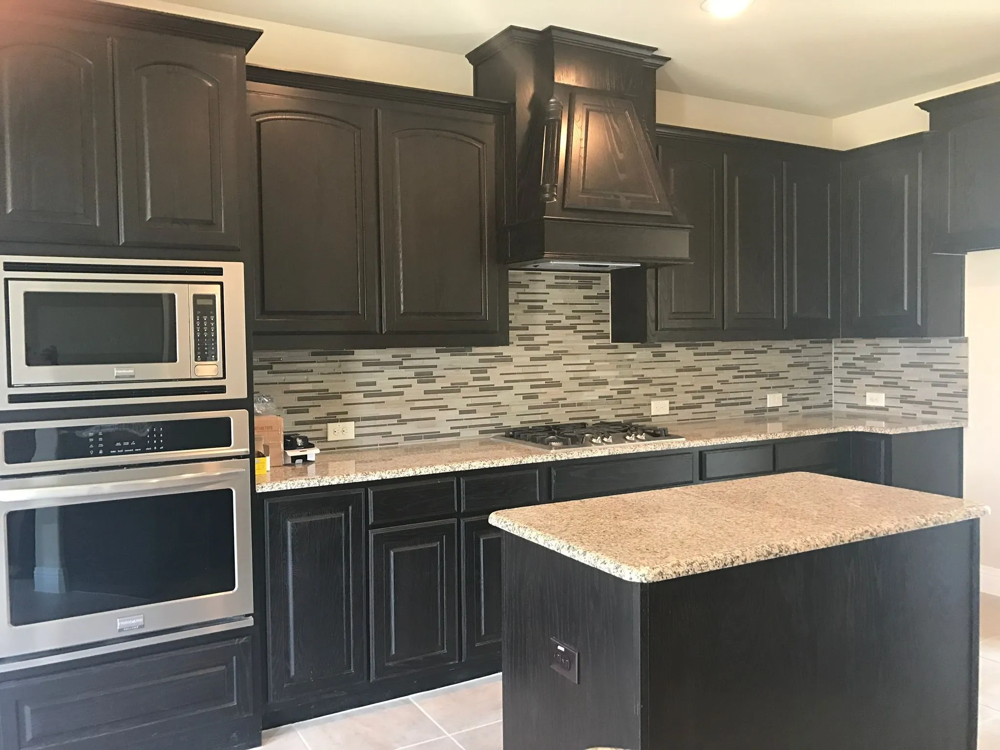 Kitchen with backsplash, custom exhaust hood, appliances with stainless steel finishes, and light tile patterned floors