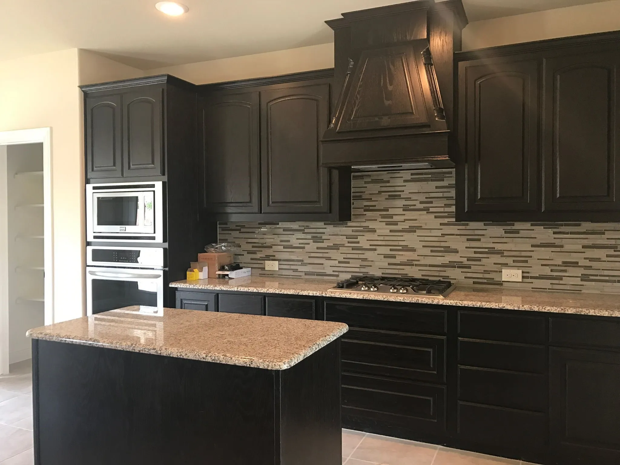 Kitchen with custom exhaust hood, stainless steel appliances, light stone counters, a kitchen island, and backsplash