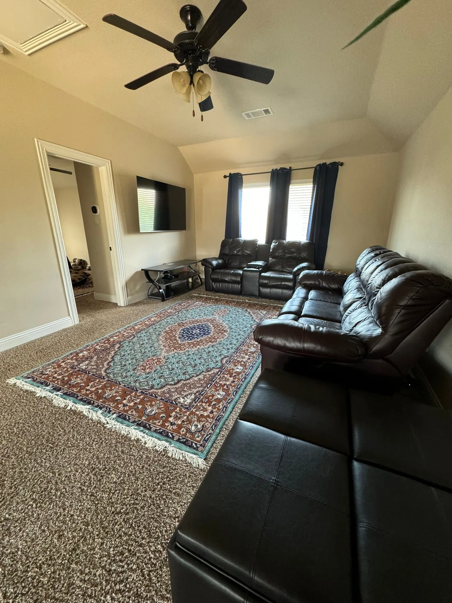 Carpeted living room with lofted ceiling and ceiling fan
