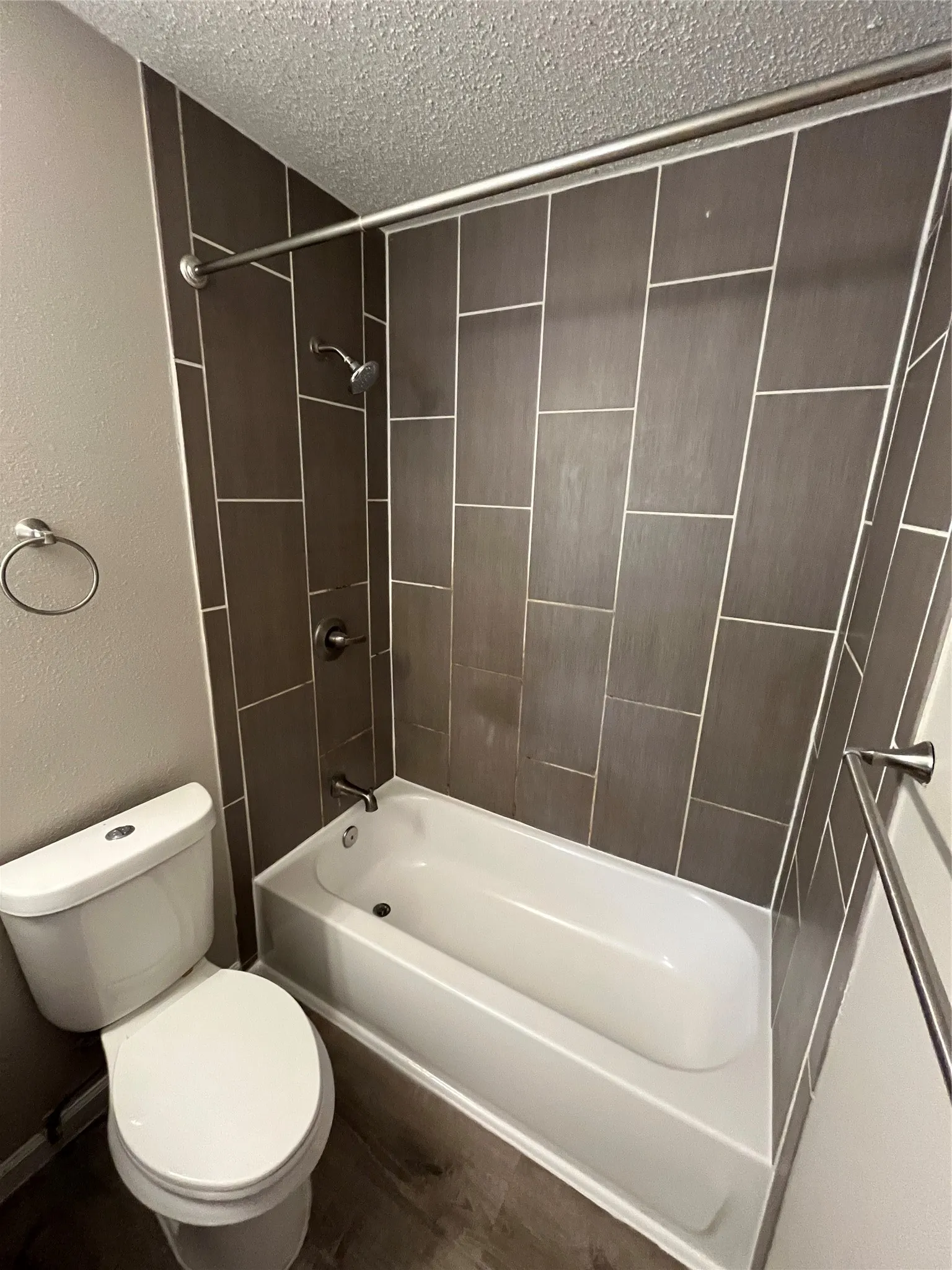 Full-size tub with shower, contemporary tiled surround, and wood-finish flooring