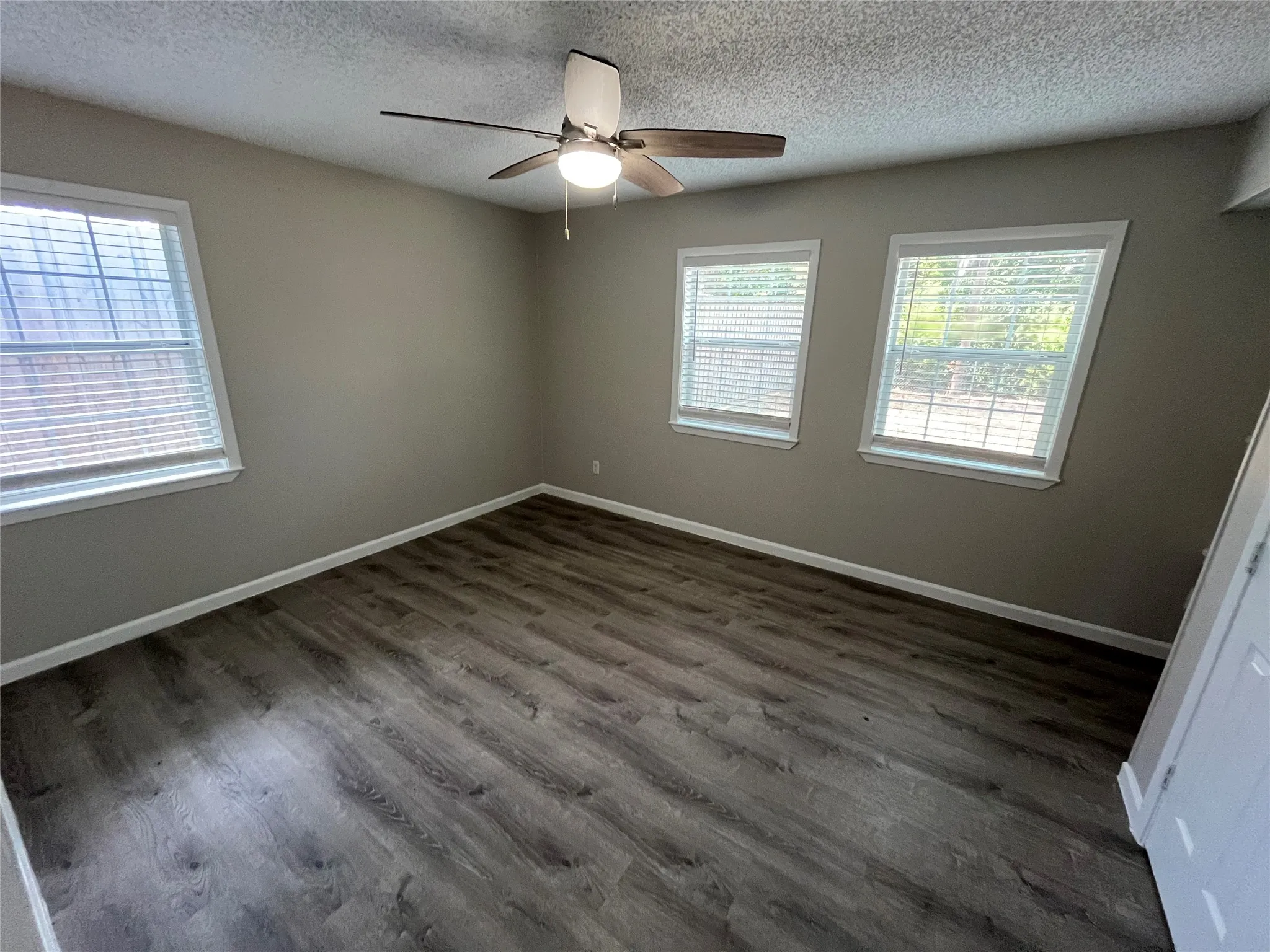 Room with wood-finish flooring, neutral wall paint, and a ceiling fan with integrated lighting