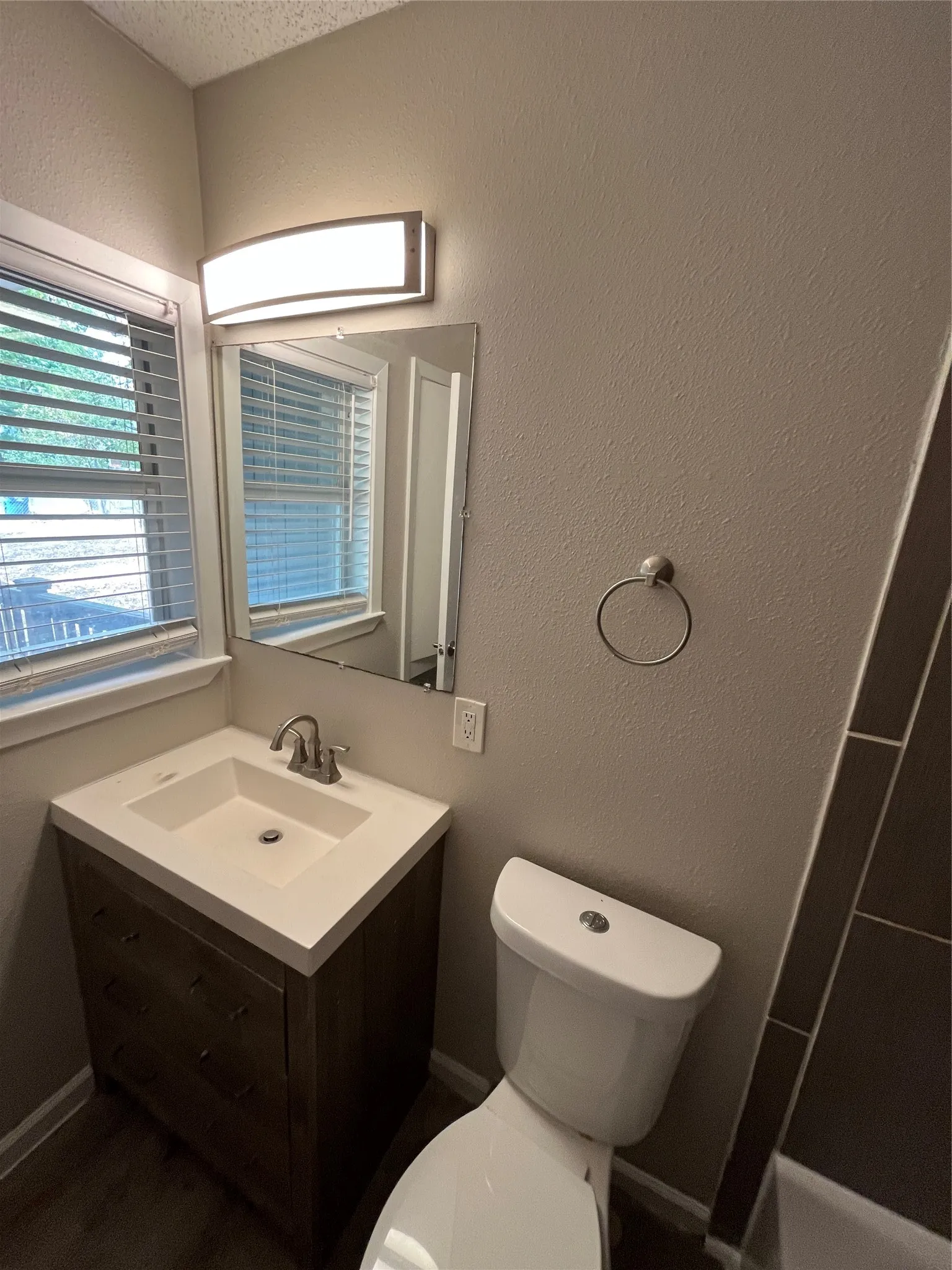 Vanity with an integrated sink, brushed nickel faucet, mirror, and sconce lighting