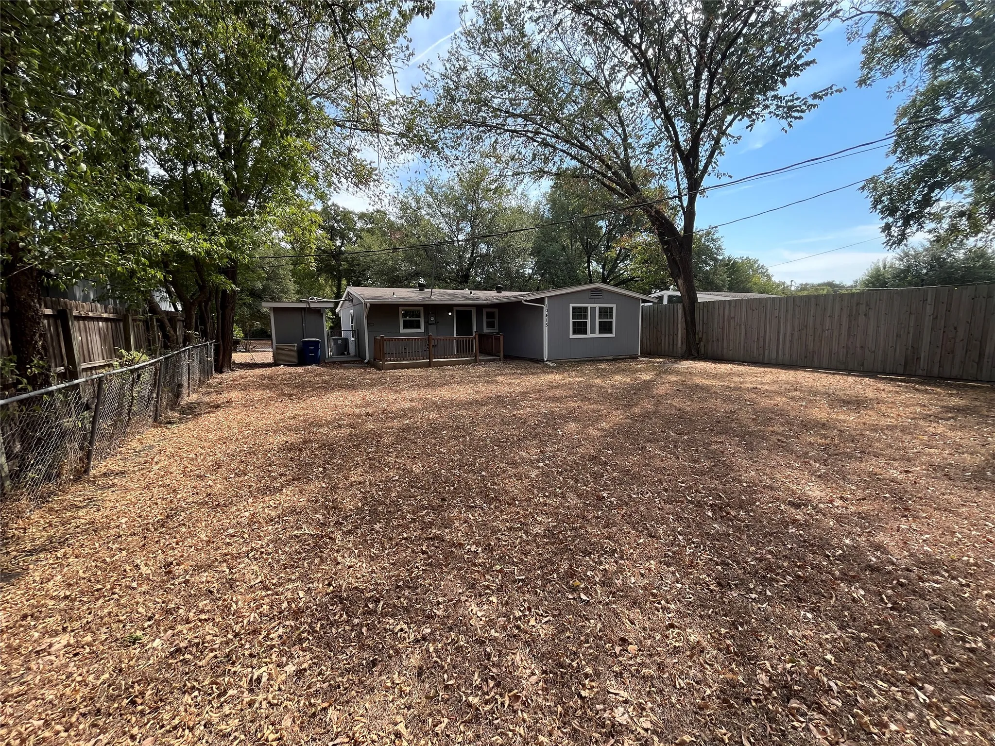Expansive backyard with a wood privacy fence, chain link fence, mature trees, and a detached storage shed