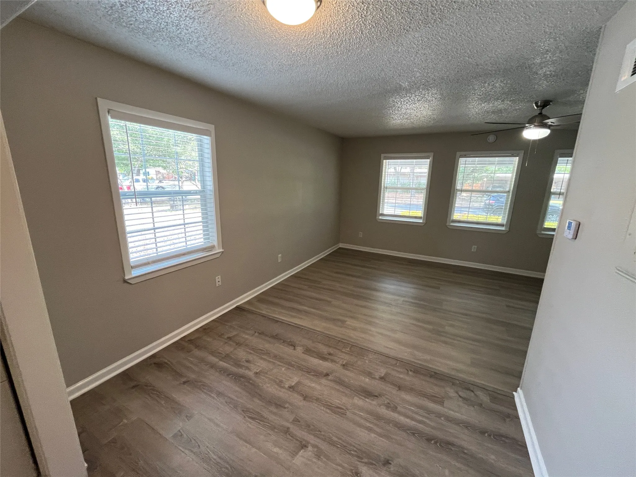 Wood-finish flooring, multiple windows with blinds, ceiling fan with integrated lighting, and recessed ceiling lighting