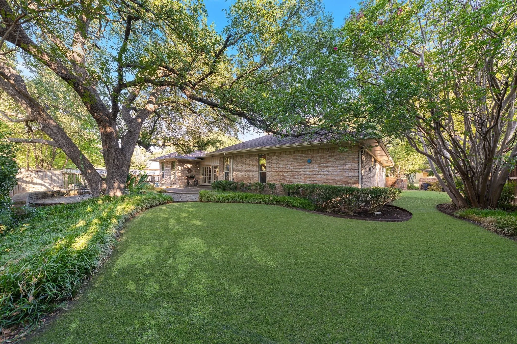 Back yard grass area with mature landscaping and trees.