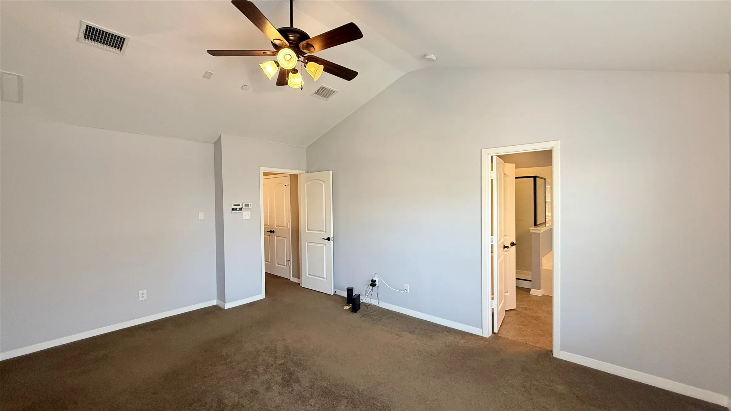 Vaulted ceiling, ceiling fan with integrated lighting, two panel doors, and neutral wall paint