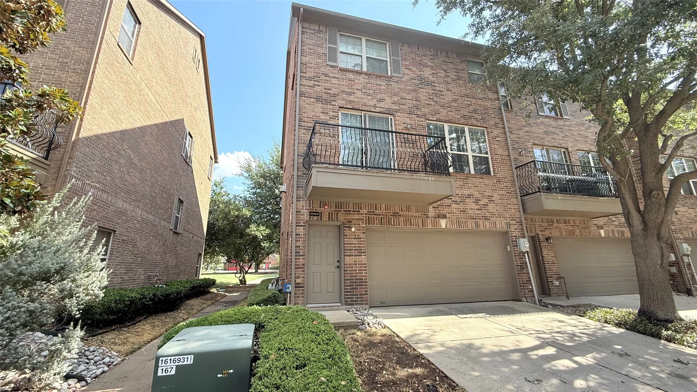 Brick exterior with a ground-level entry, an attached garage, and a second-story balcony with wrought iron railing