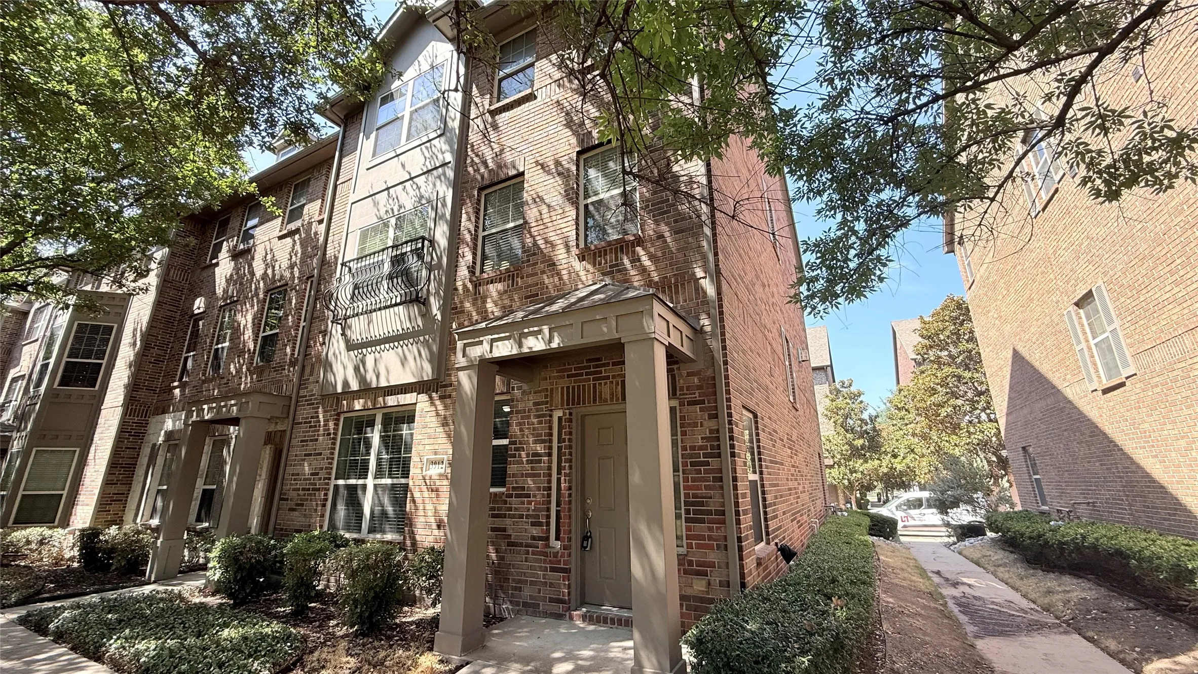 Brick facade townhome with multi-pane windows and a covered entry