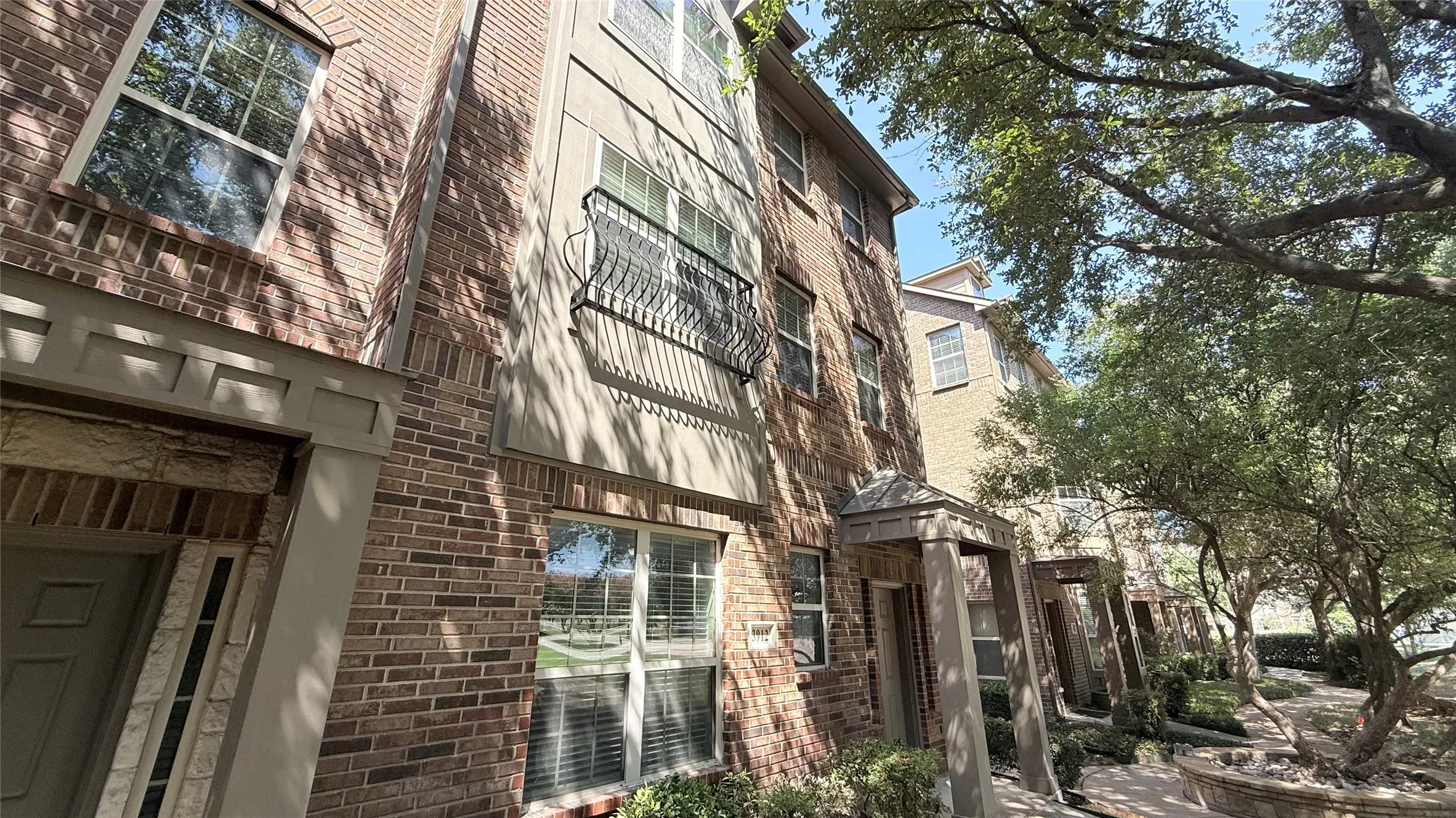 Brick exterior with stucco accents, multi-pane windows, and decorative wrought iron balcony railing