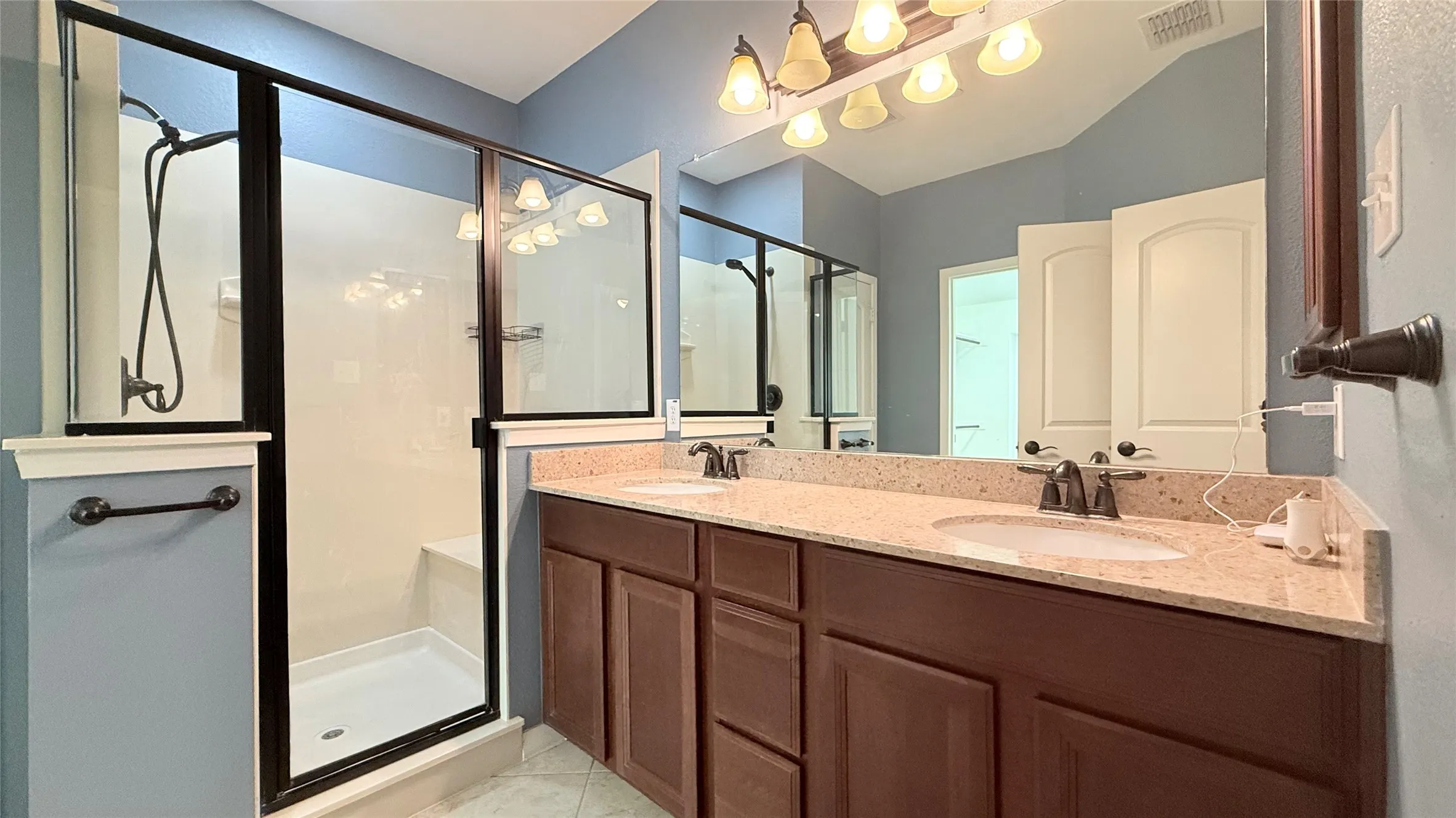 Dual vanity with a stone-finish countertop, undermount sinks, and dark wood-finish cabinetry