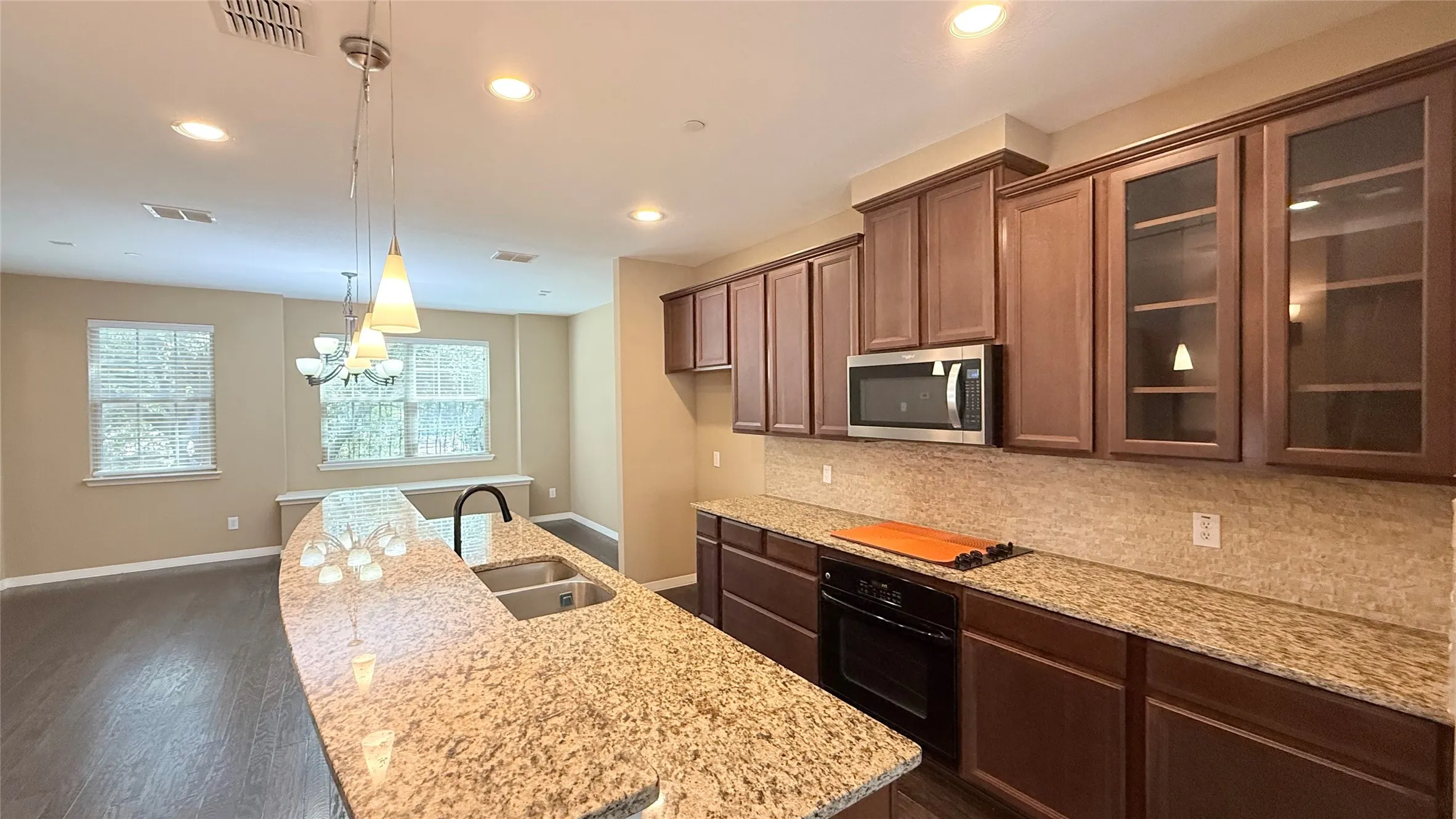 Kitchen featuring granite countertops, stainless steel appliances, wood-finish cabinetry, and recessed lighting