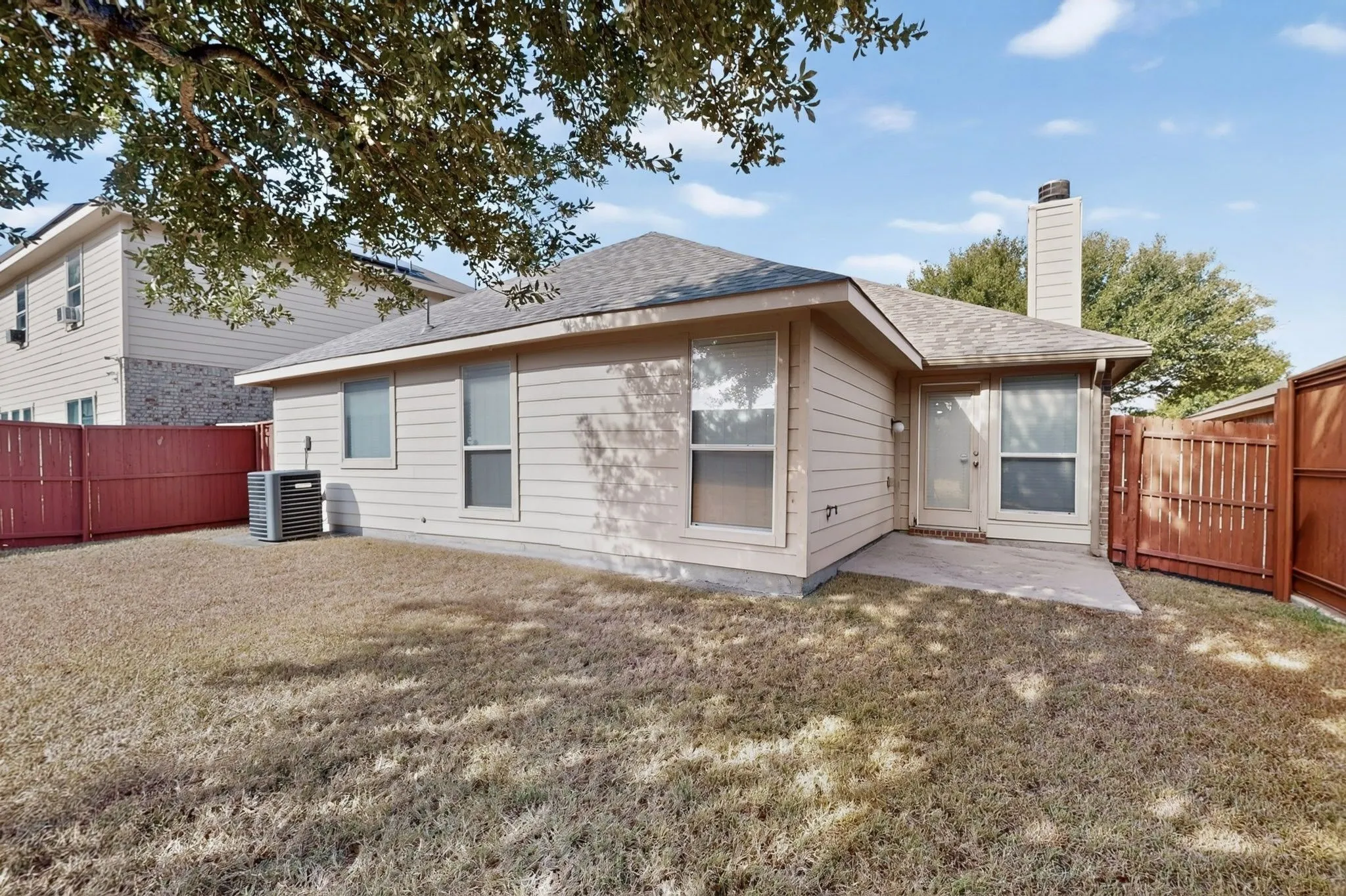 Exterior siding with prominent windows, a concrete patio, and a privacy fence