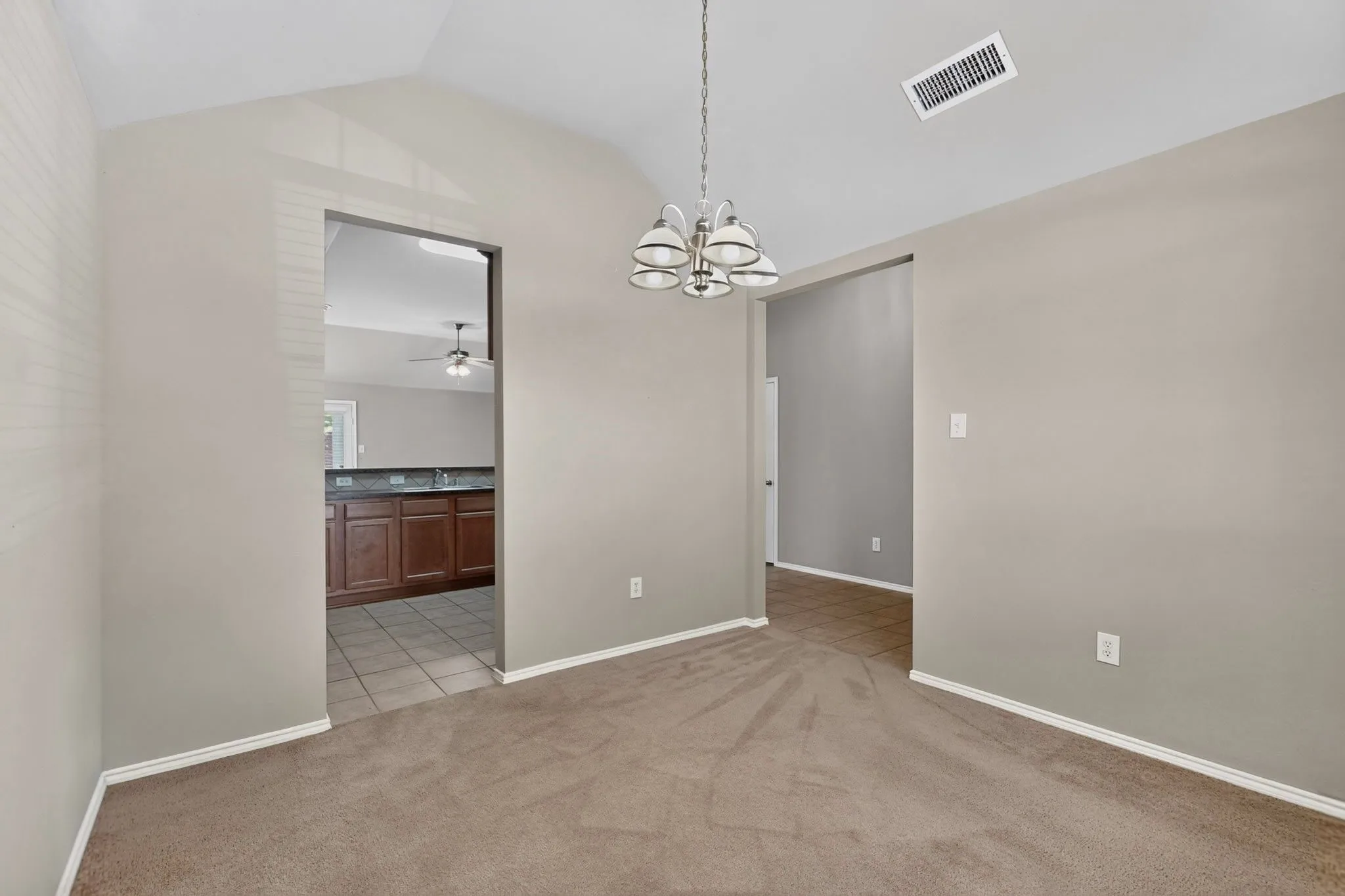 Vaulted ceiling, carpet flooring, and a chandelier with bowl-shaped shades