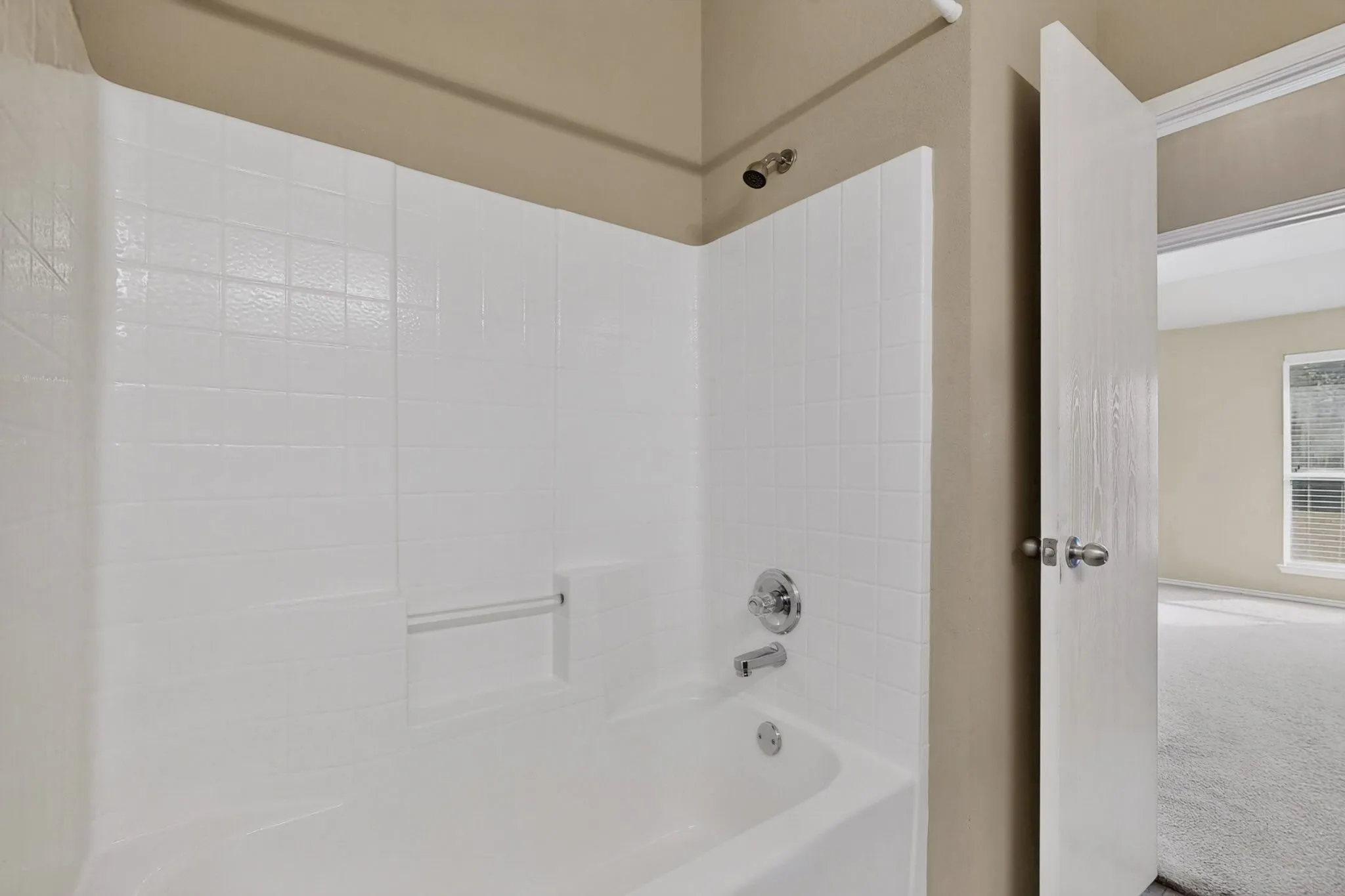 Bathtub with white subway tile surround, chrome fixtures, and a mounted showerhead