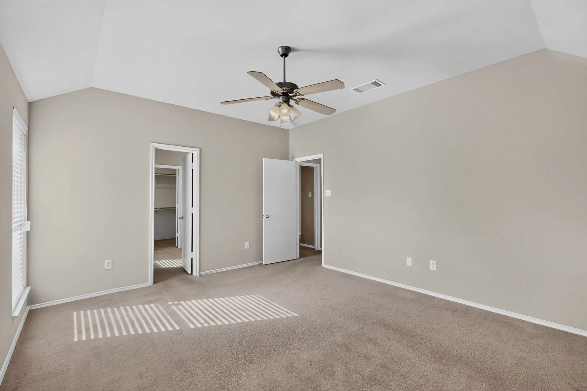 Vaulted ceiling with a ceiling fan, neutral wall paint, and plush carpet flooring